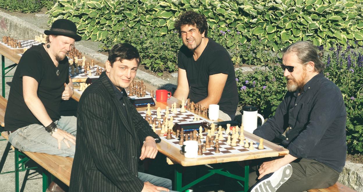 Four men playing chess in Ila parken on a sunny summer day.