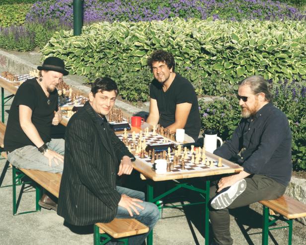 Four people gathered around two chess boards in a park in Trondheim