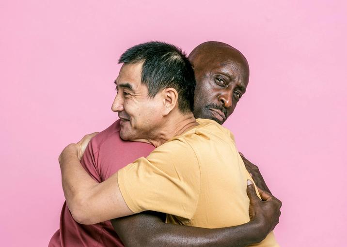 Two men greeting hugging, one of them is not so pleased