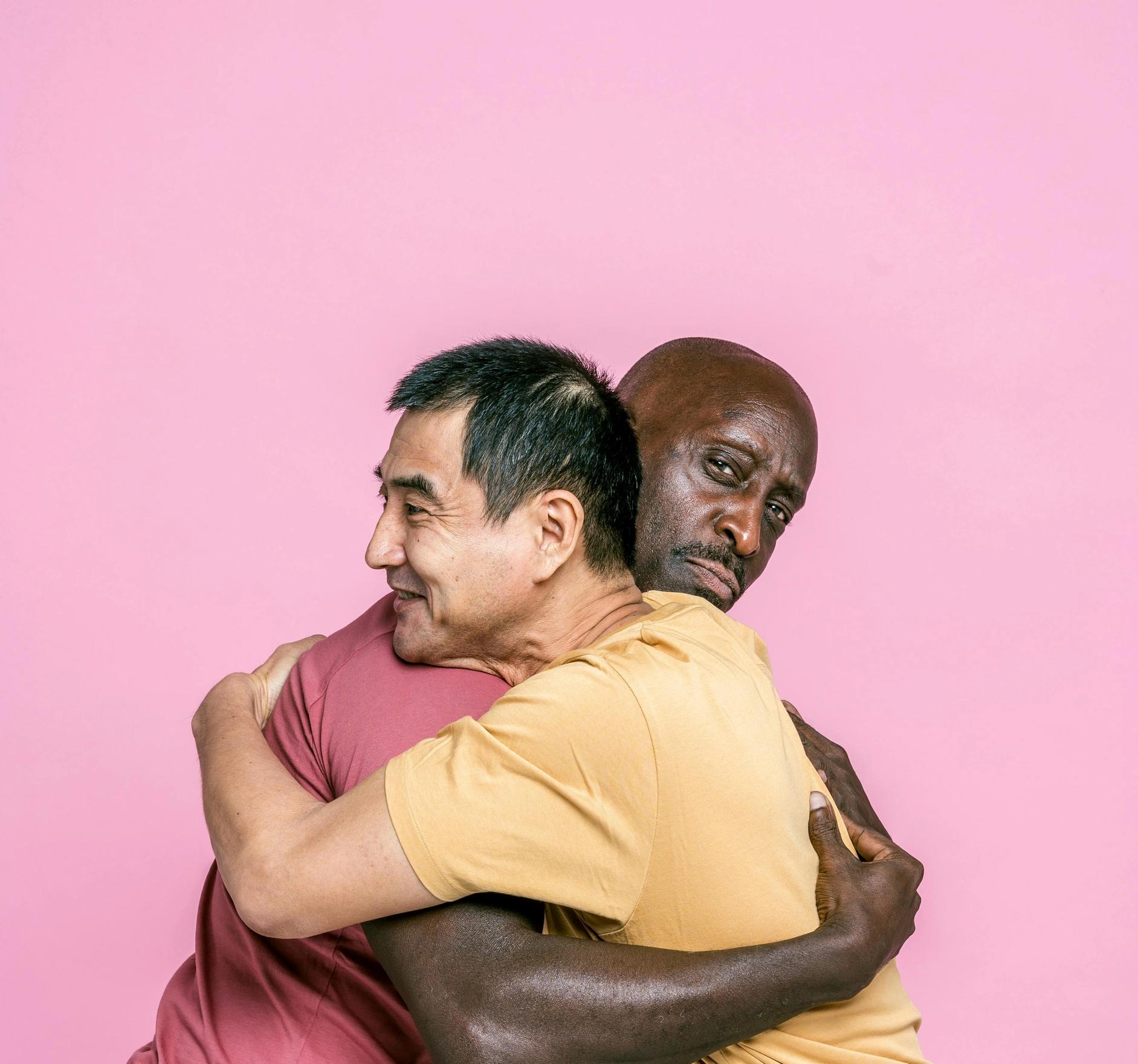 Two men greeting hugging, one of them is not so pleased