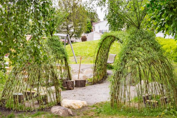 Small huts made with living trees bound together in a park.