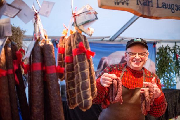 A jolly man in a red sweater showing off his wares - sausages.