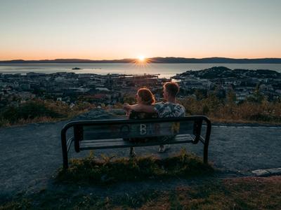 Two people sitting on a bench during sunset.