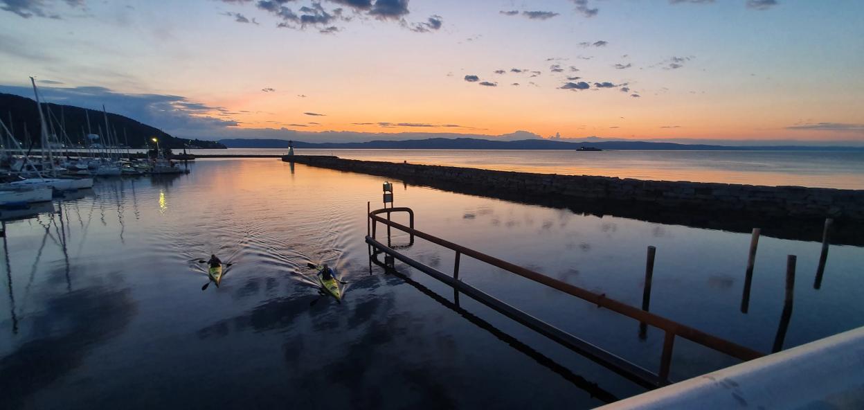 Kayakers at a calm fjord sunset evening