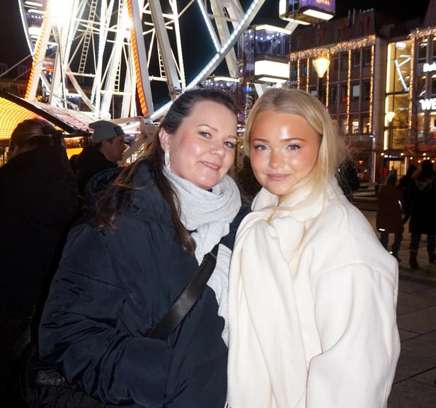 Two women standing in front of a lit up ferris-wheel