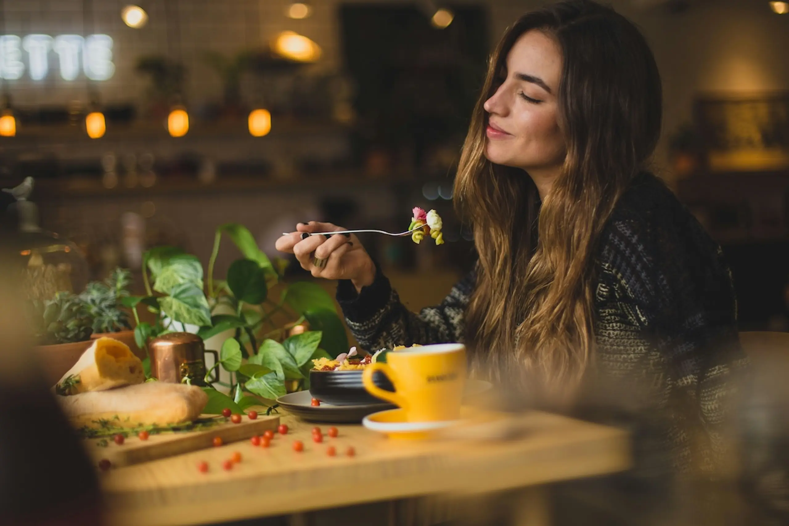 woman eating in a cafe with a cup of coffee next to her