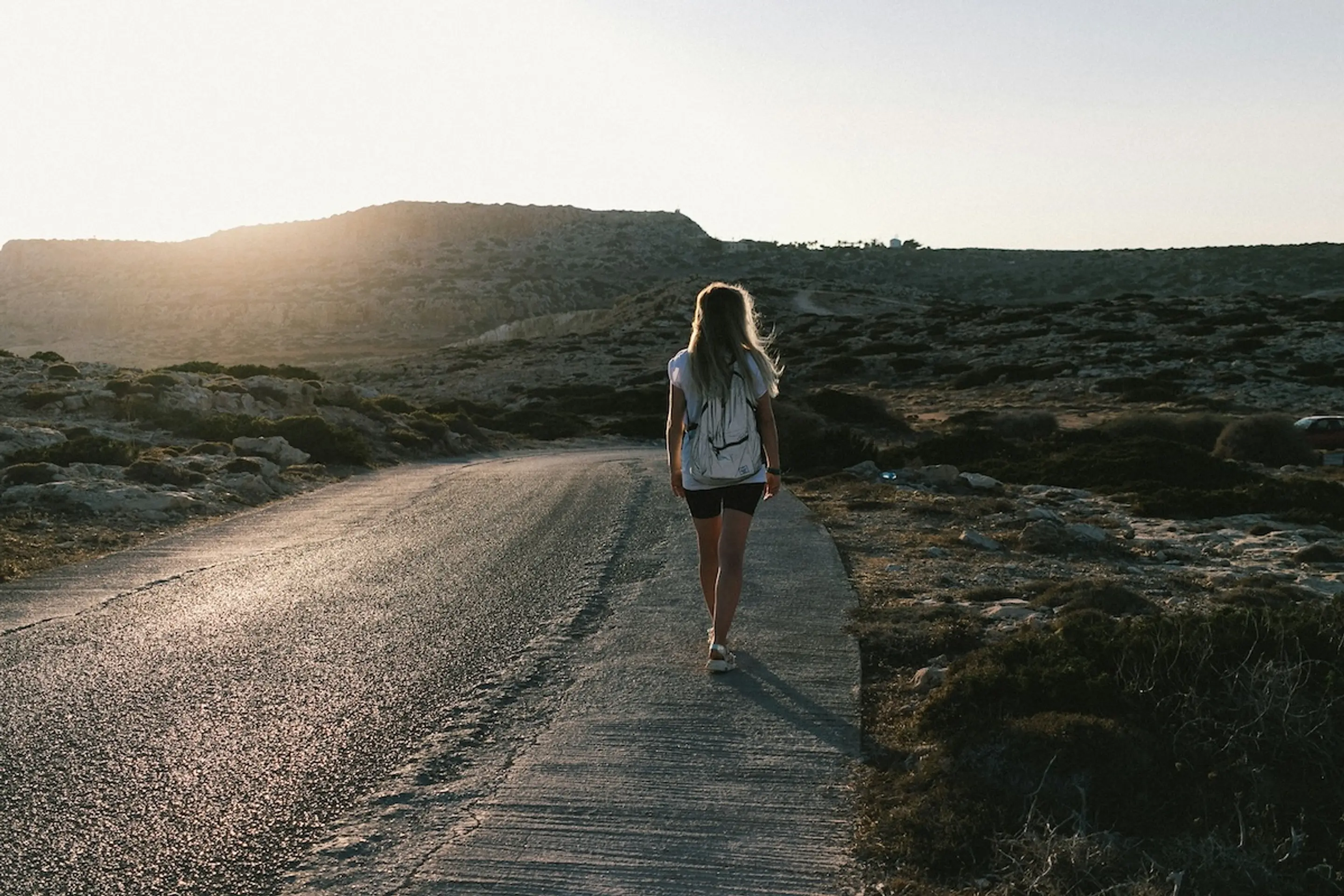 woman walking down road with backpack