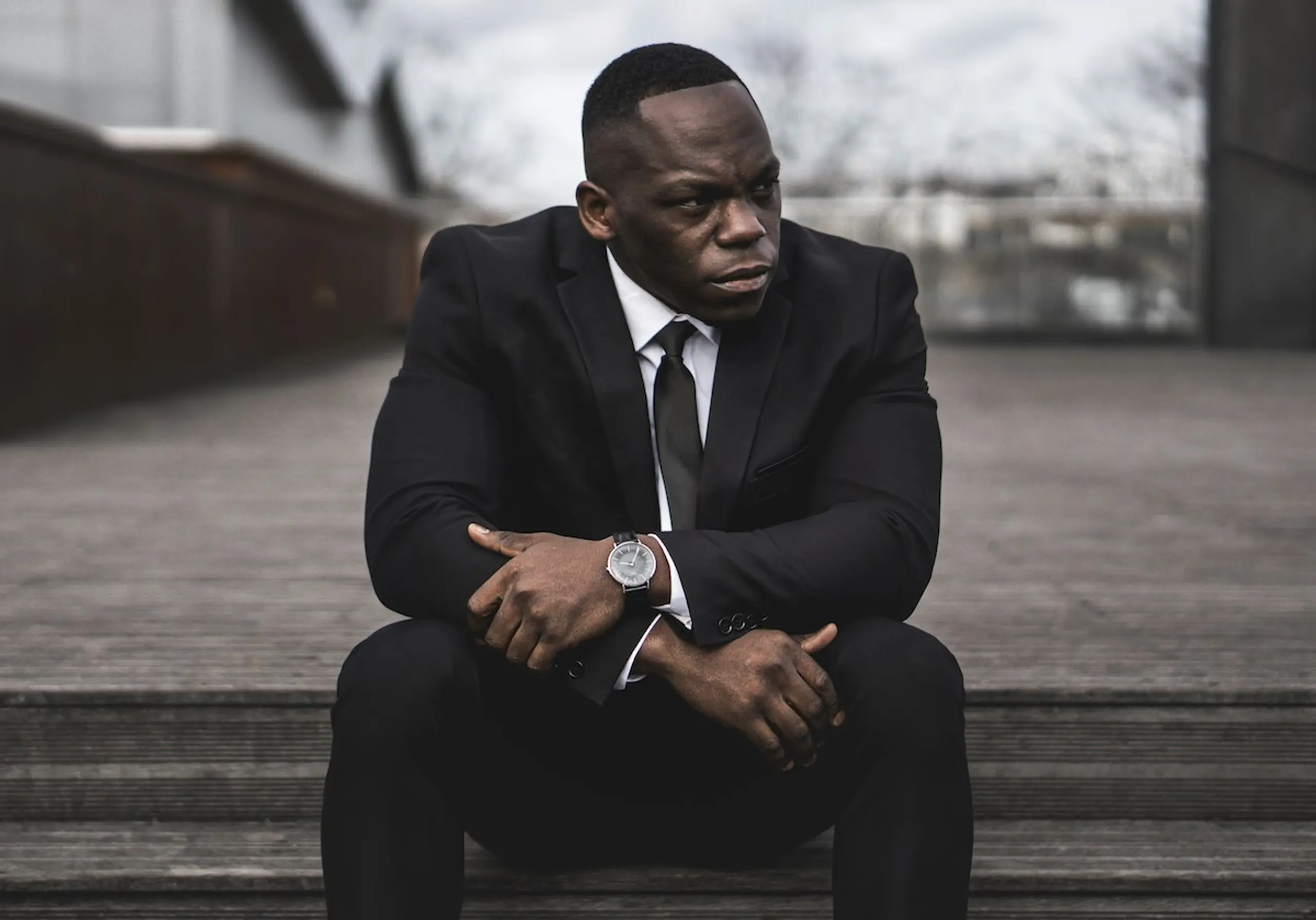 A man in a suit sitting on the steps outside