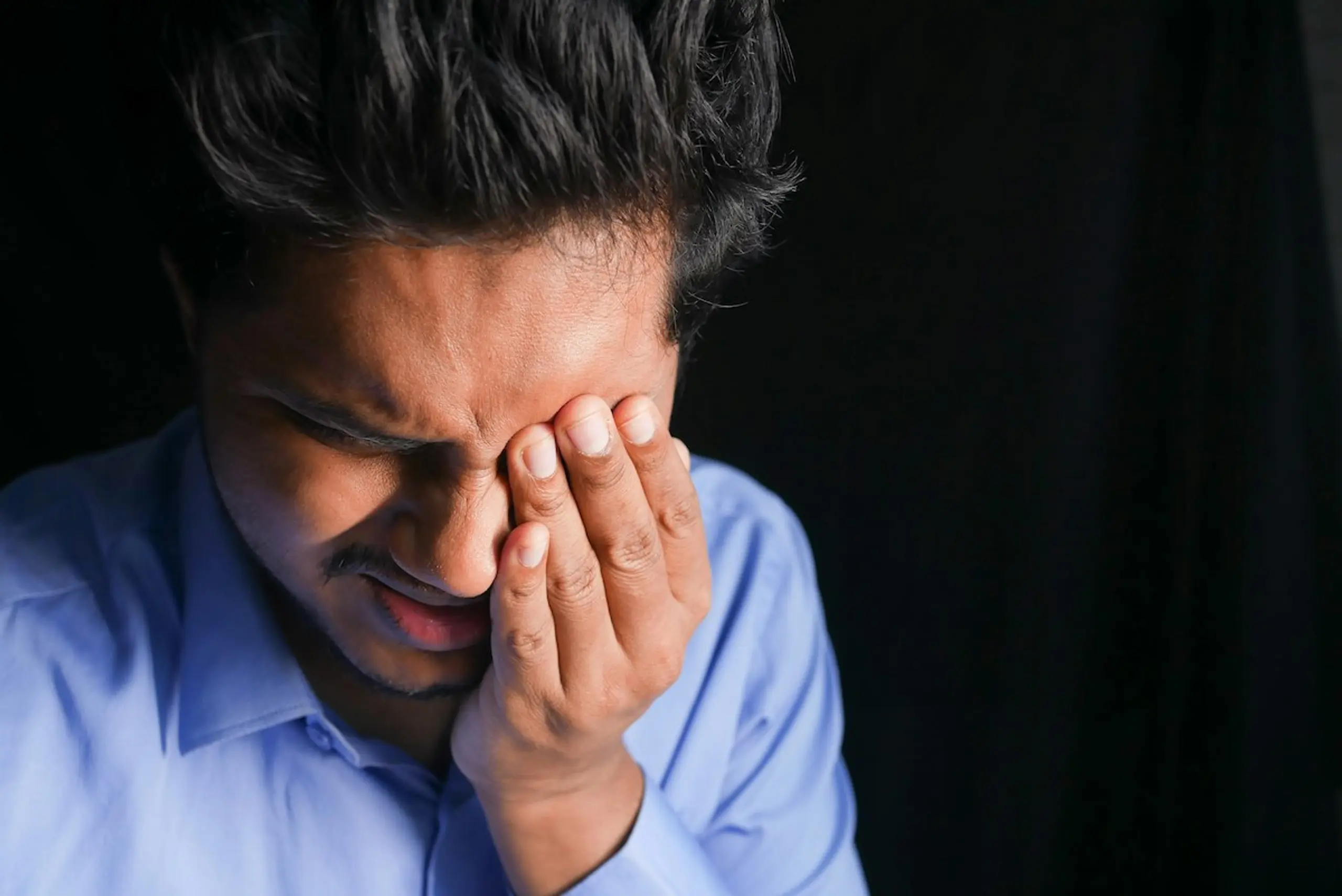 A stressed man rubbing his eye