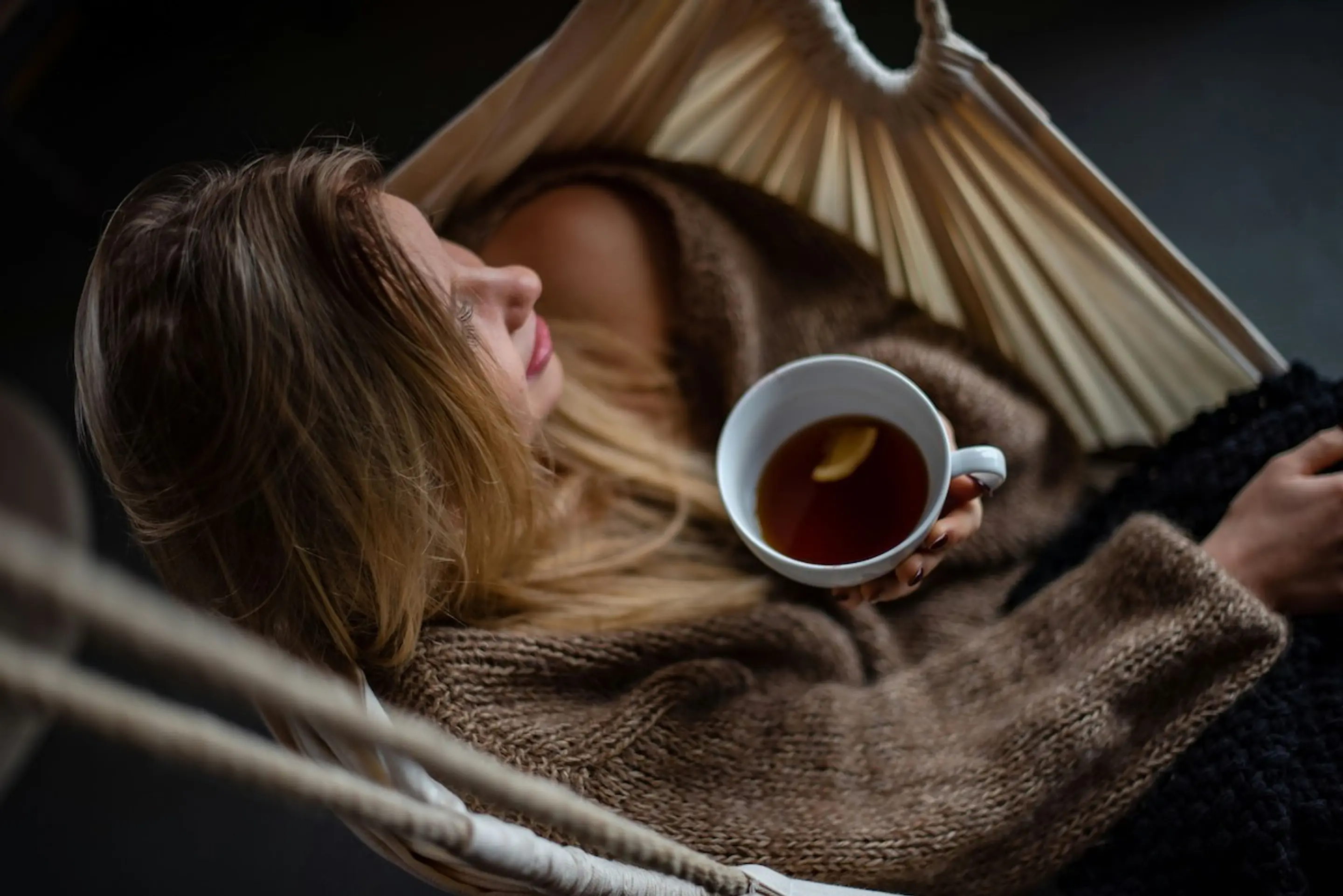 A woman drinking tea in a hammock