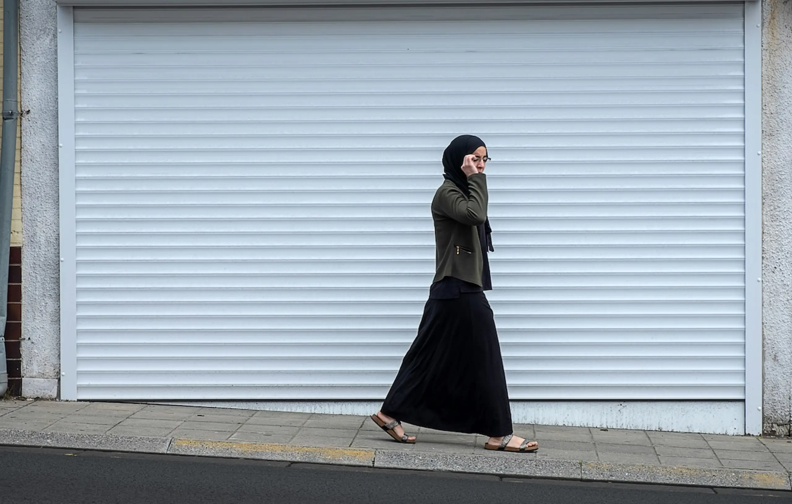 woman walking on street in front of garage