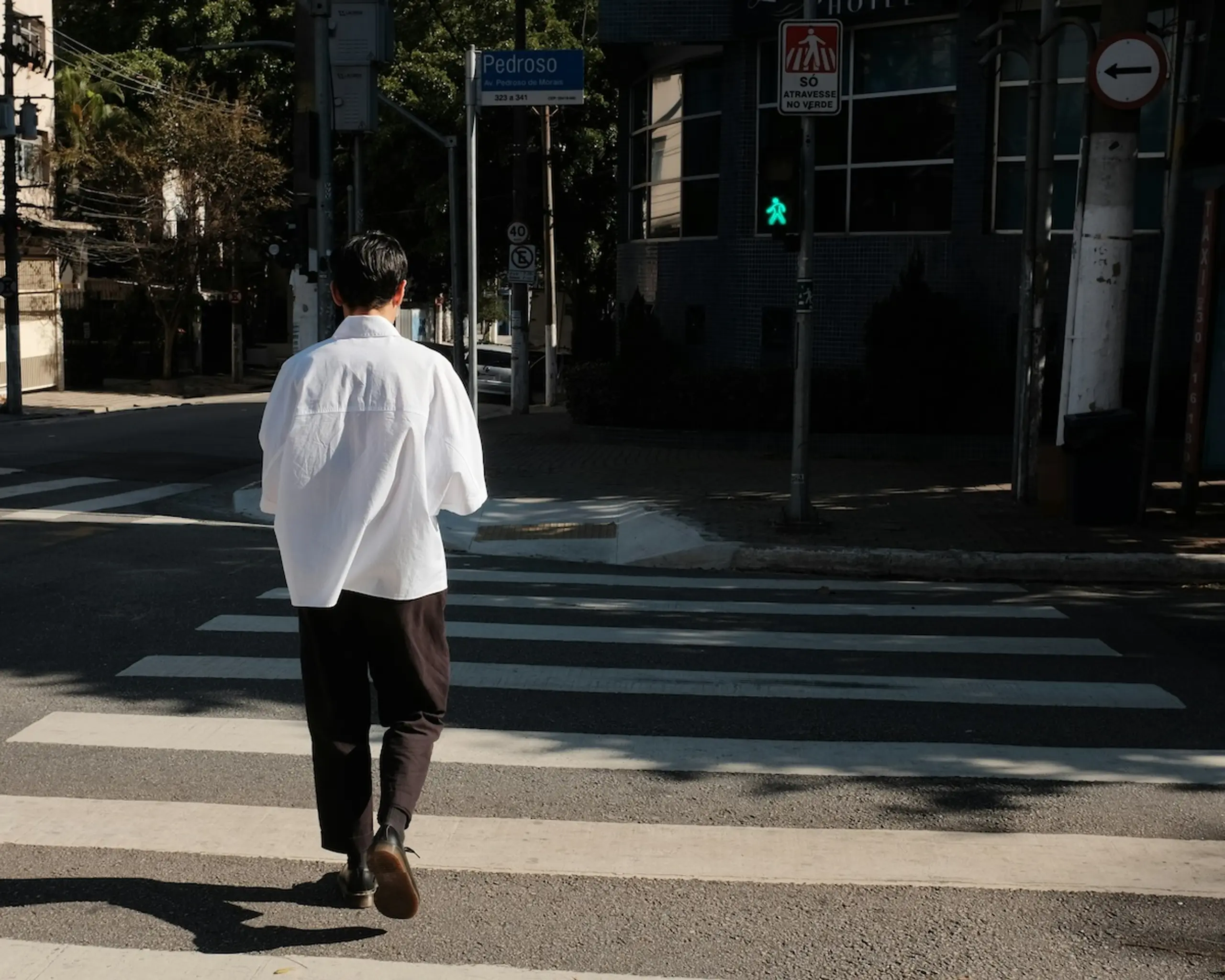 man walking in crosswalk on street