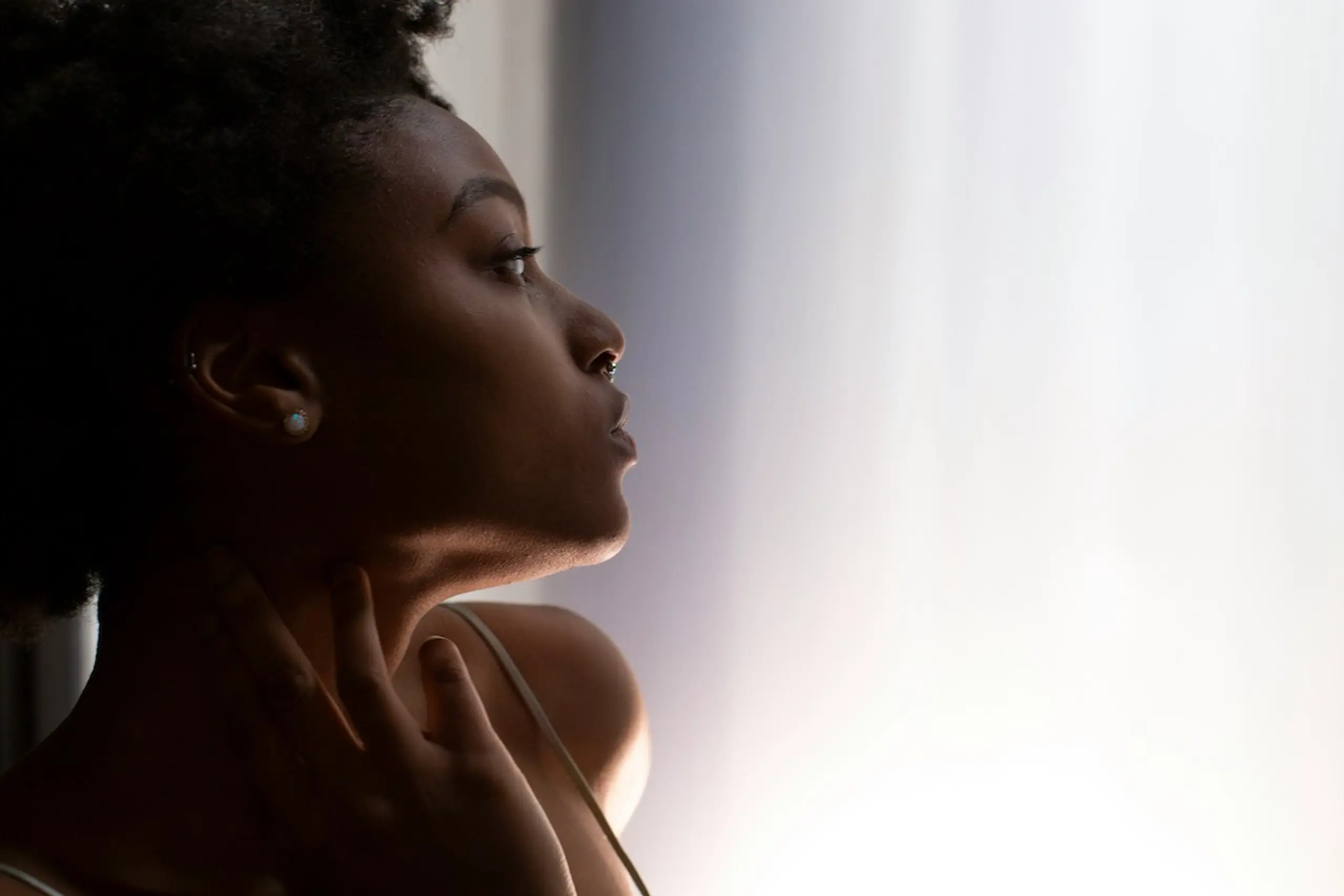 A woman touching her neck and looking out the window