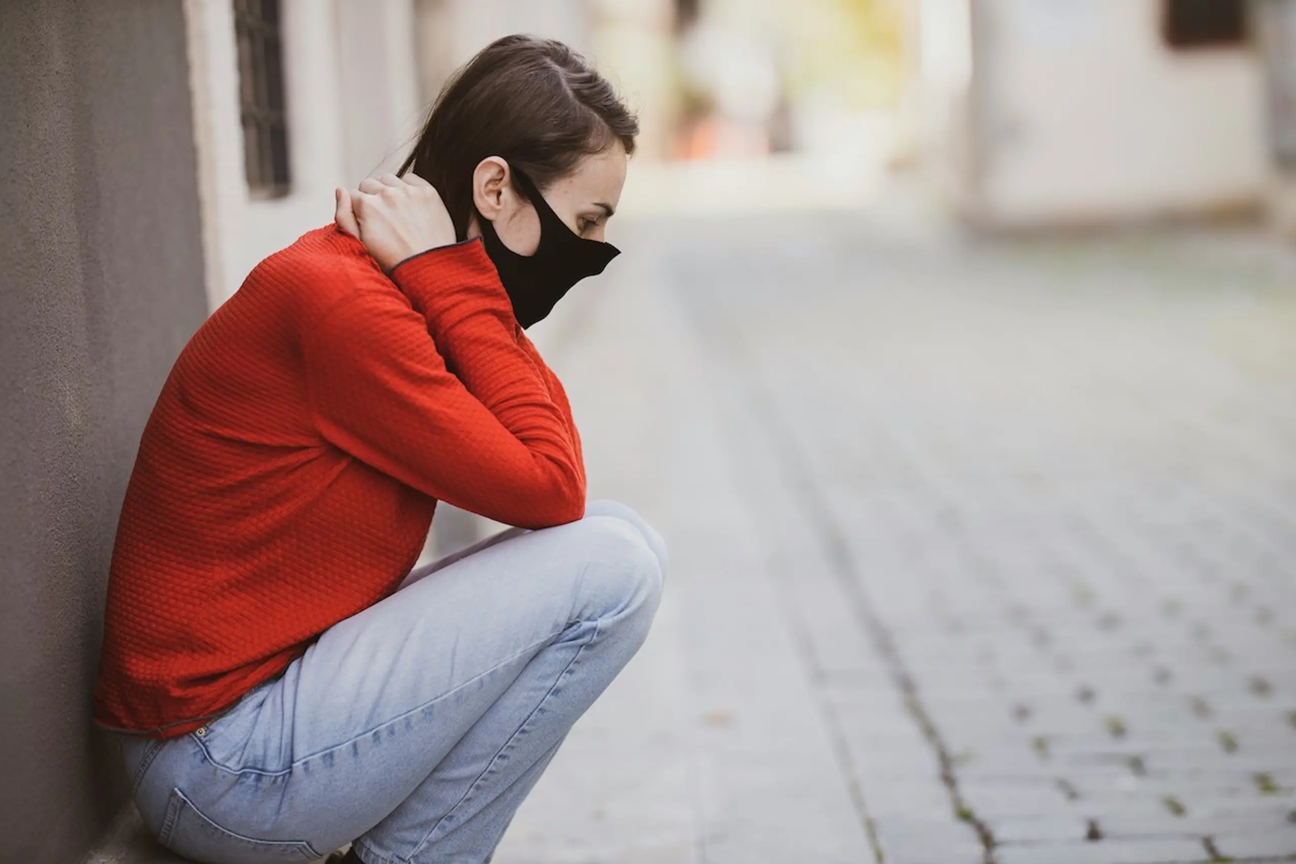 woman crouching over in pain in an alley