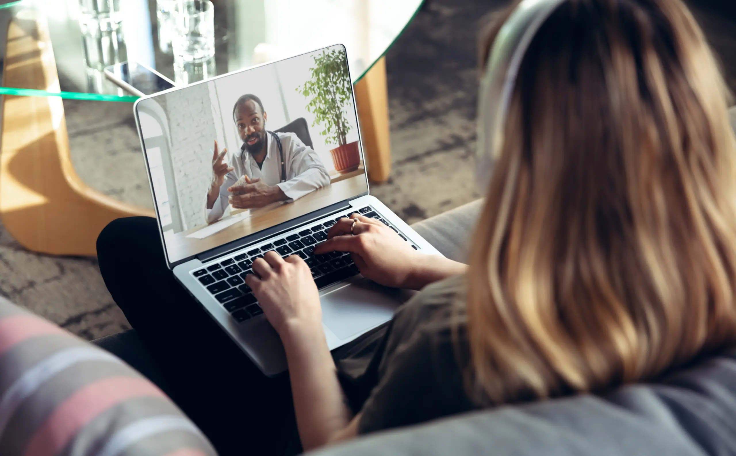Woman on laptop has telehealth session with a doctor