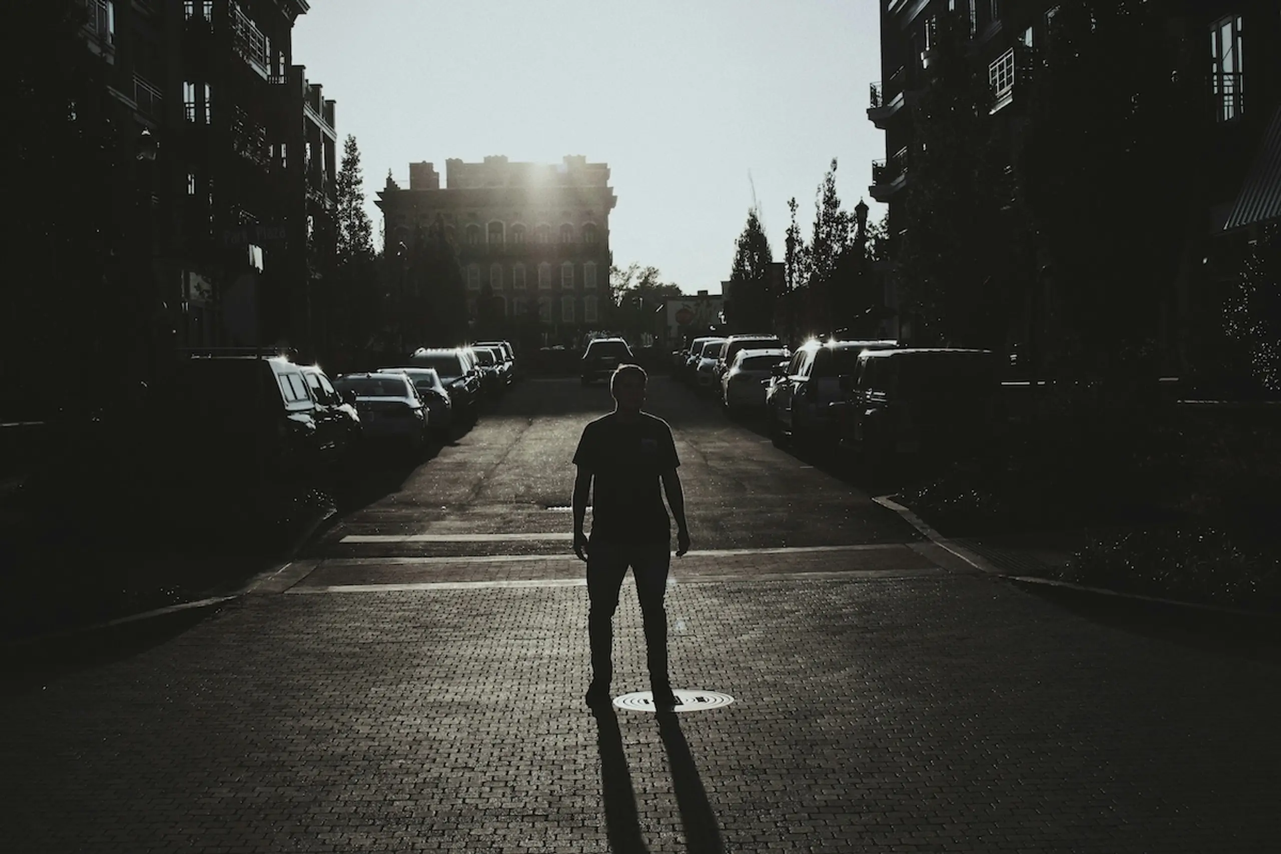 man standing in road looking at building and cars