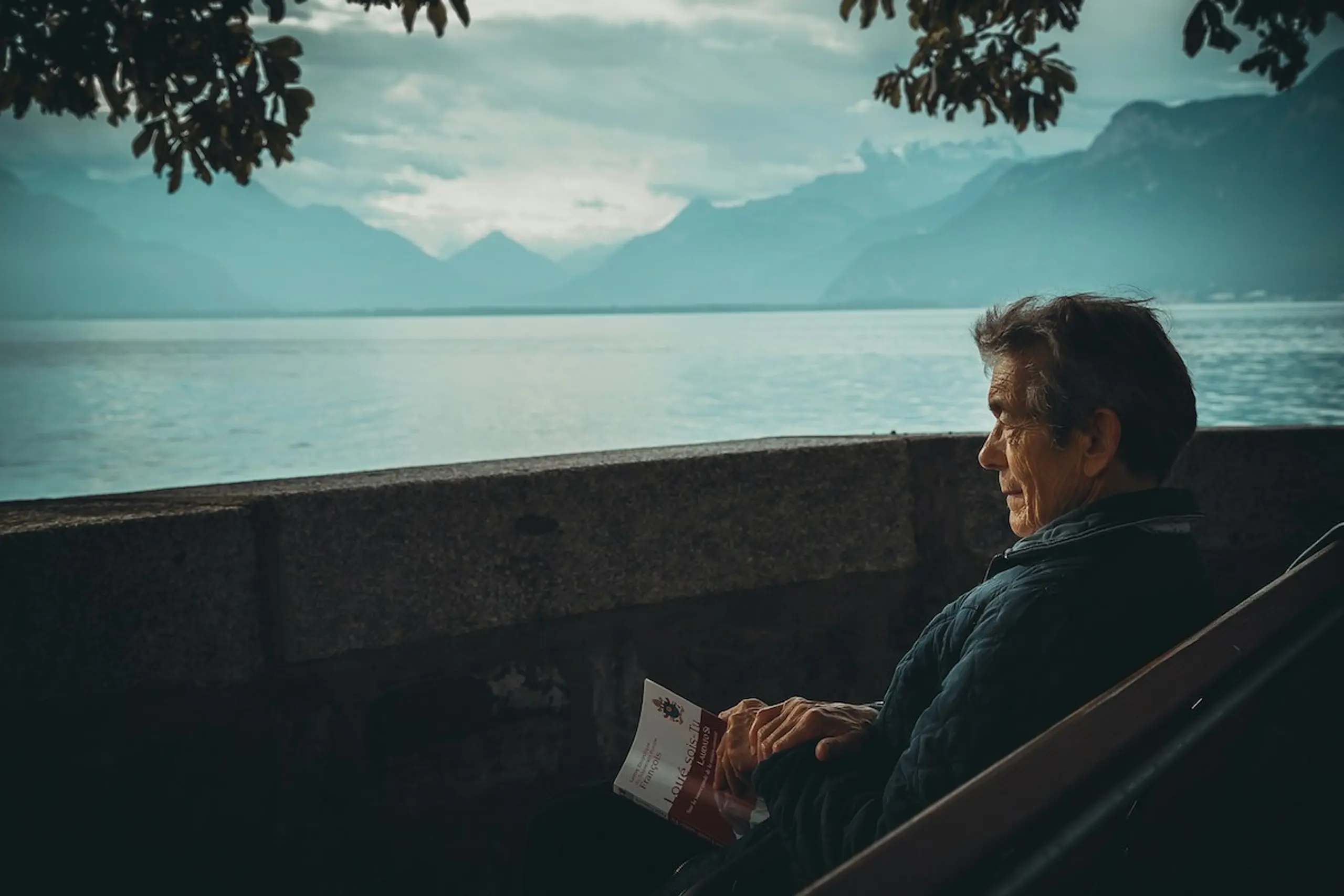 An older man sitting and looking out at a lake