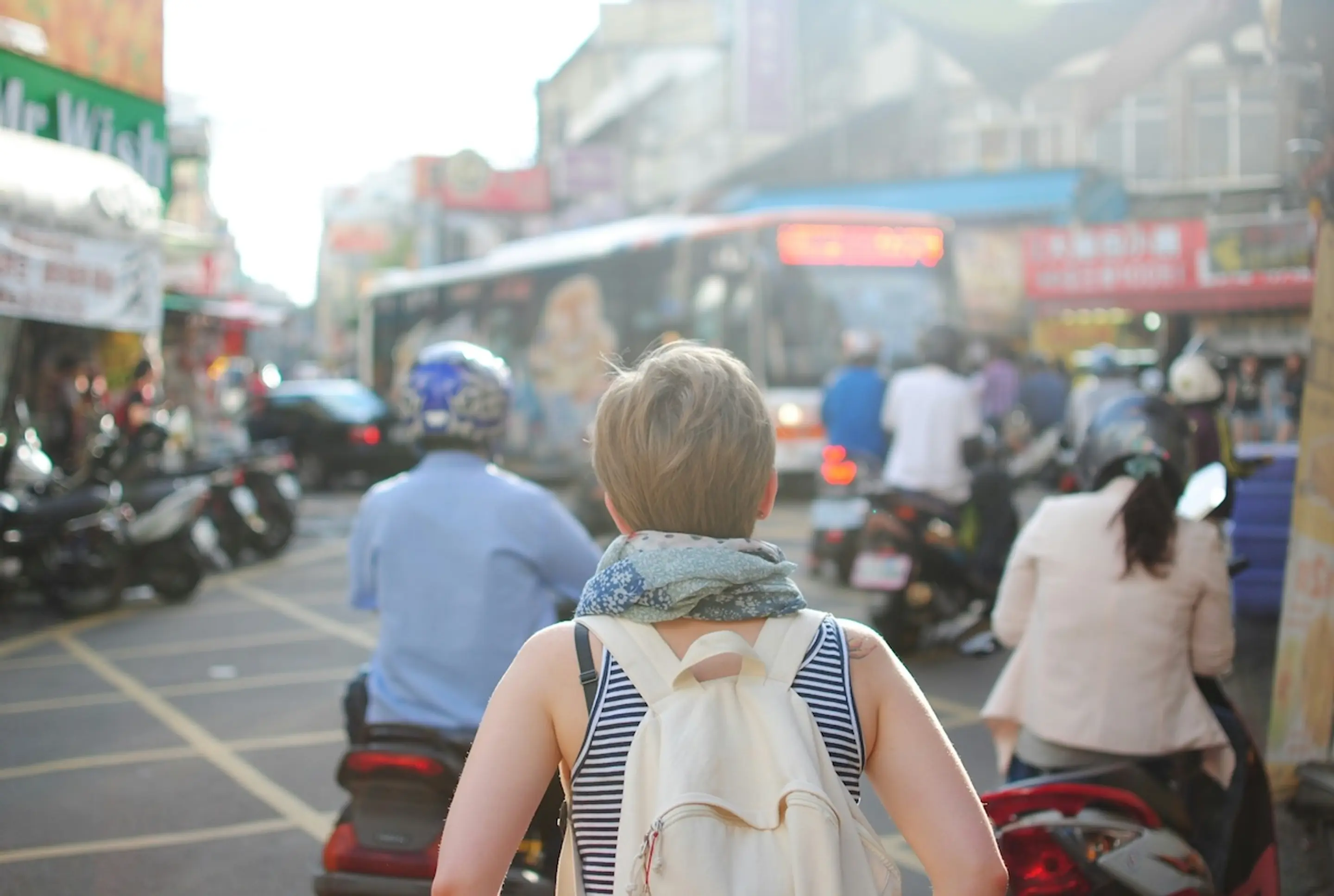 People in a busy city scene with motorcycles and buses next to buildings