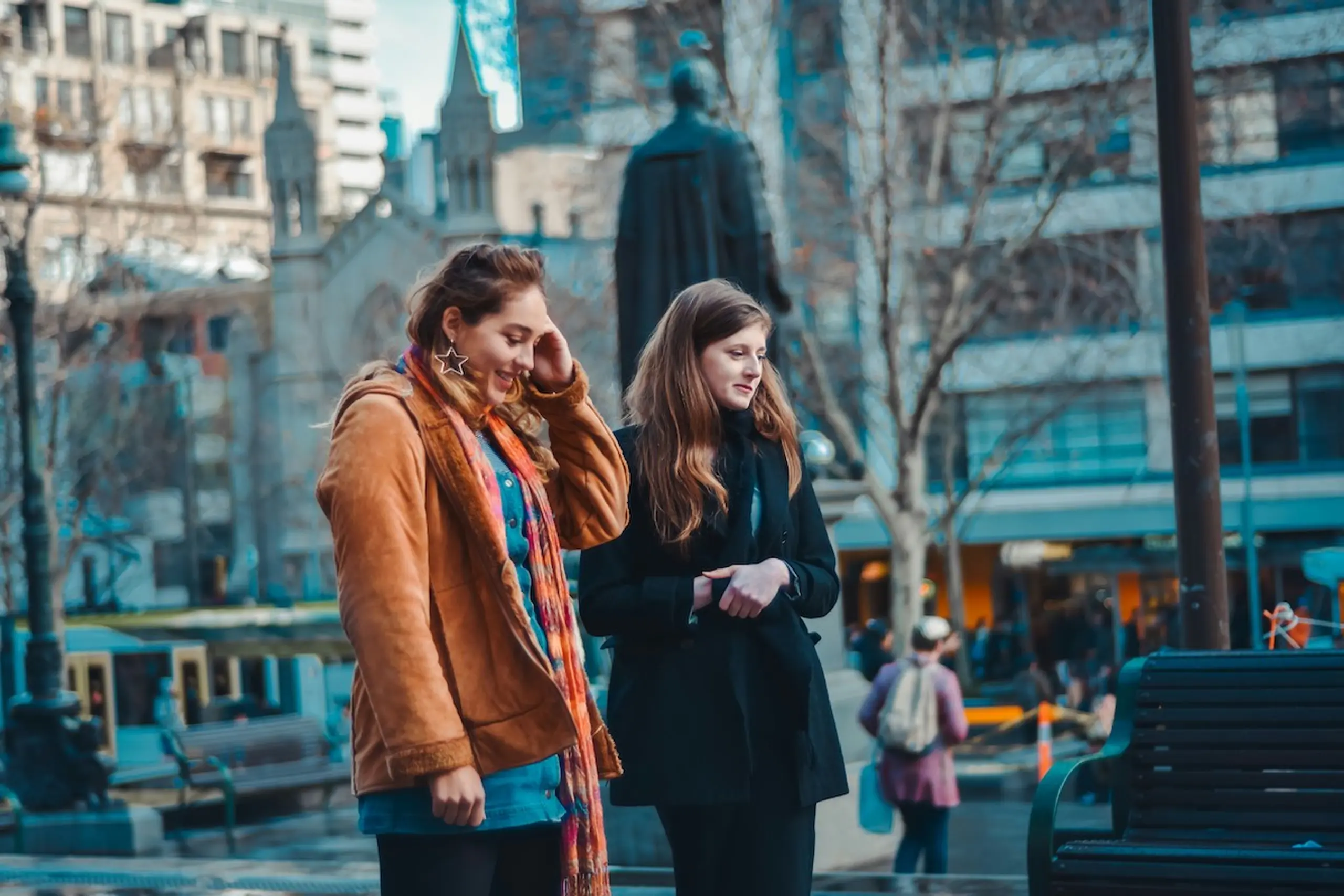 Two women walking talking to each other in confidence outside