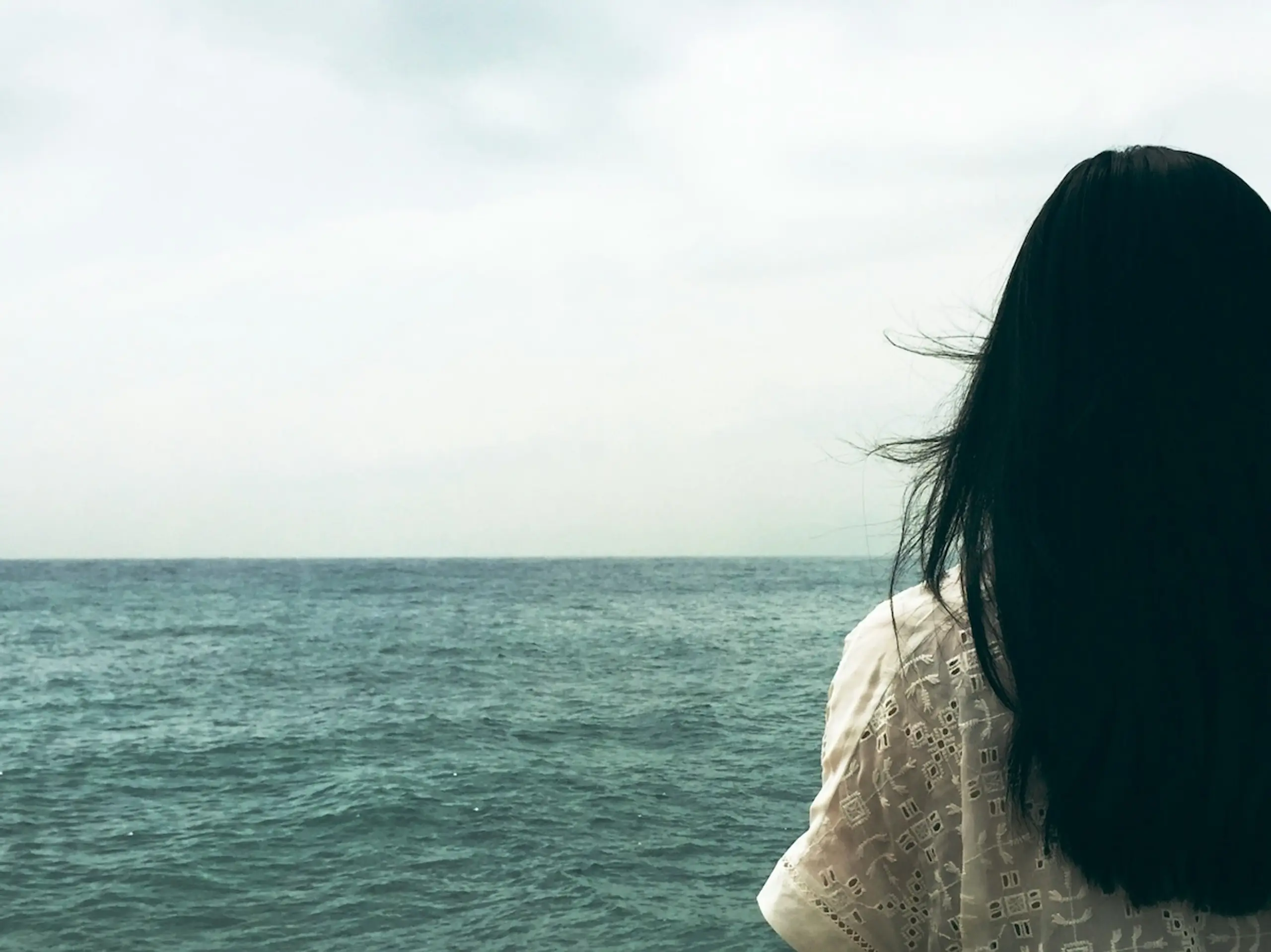 woman looking at water with cloudy sky