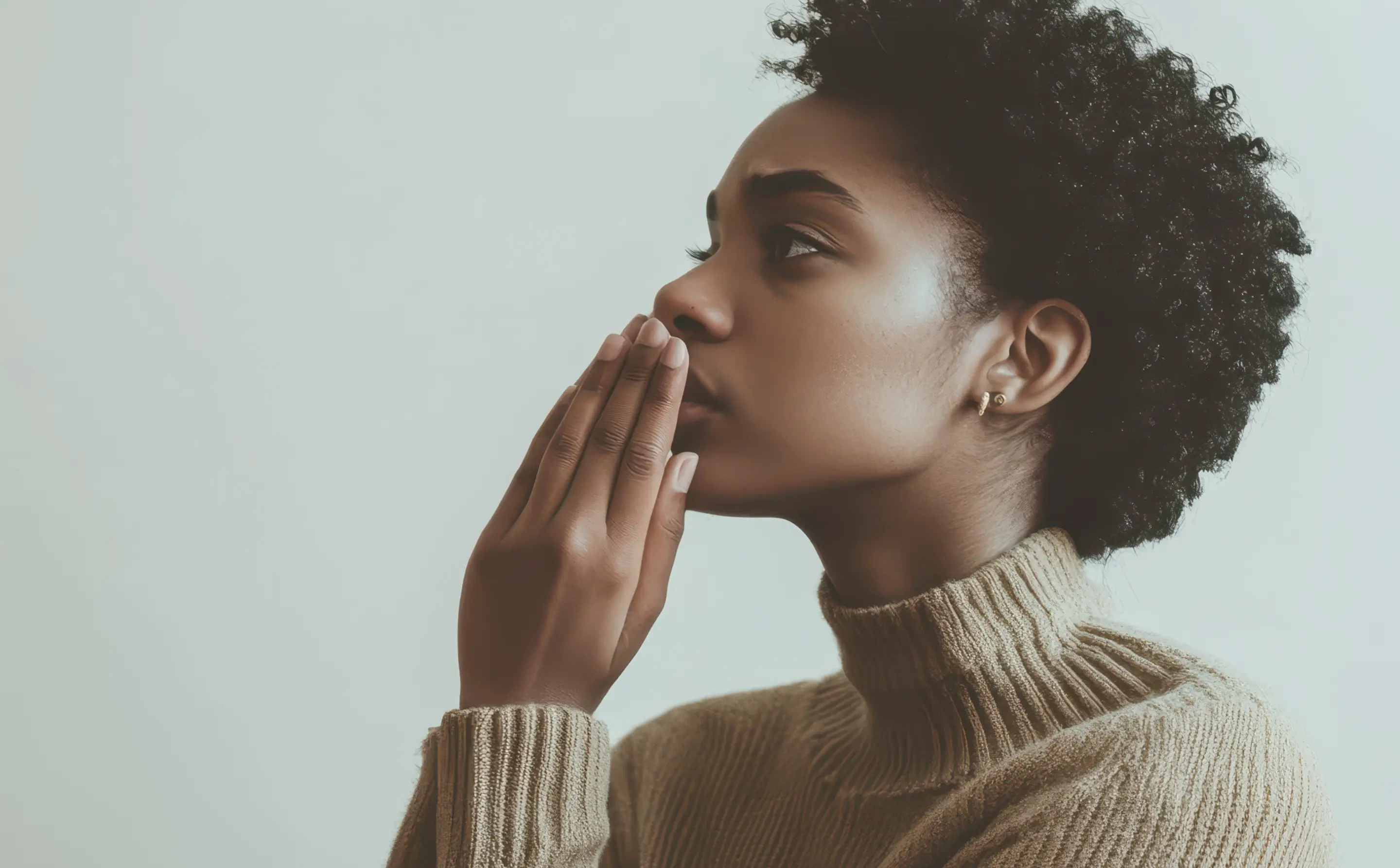 Woman with Afro wearing turtleneck and touching her mouth