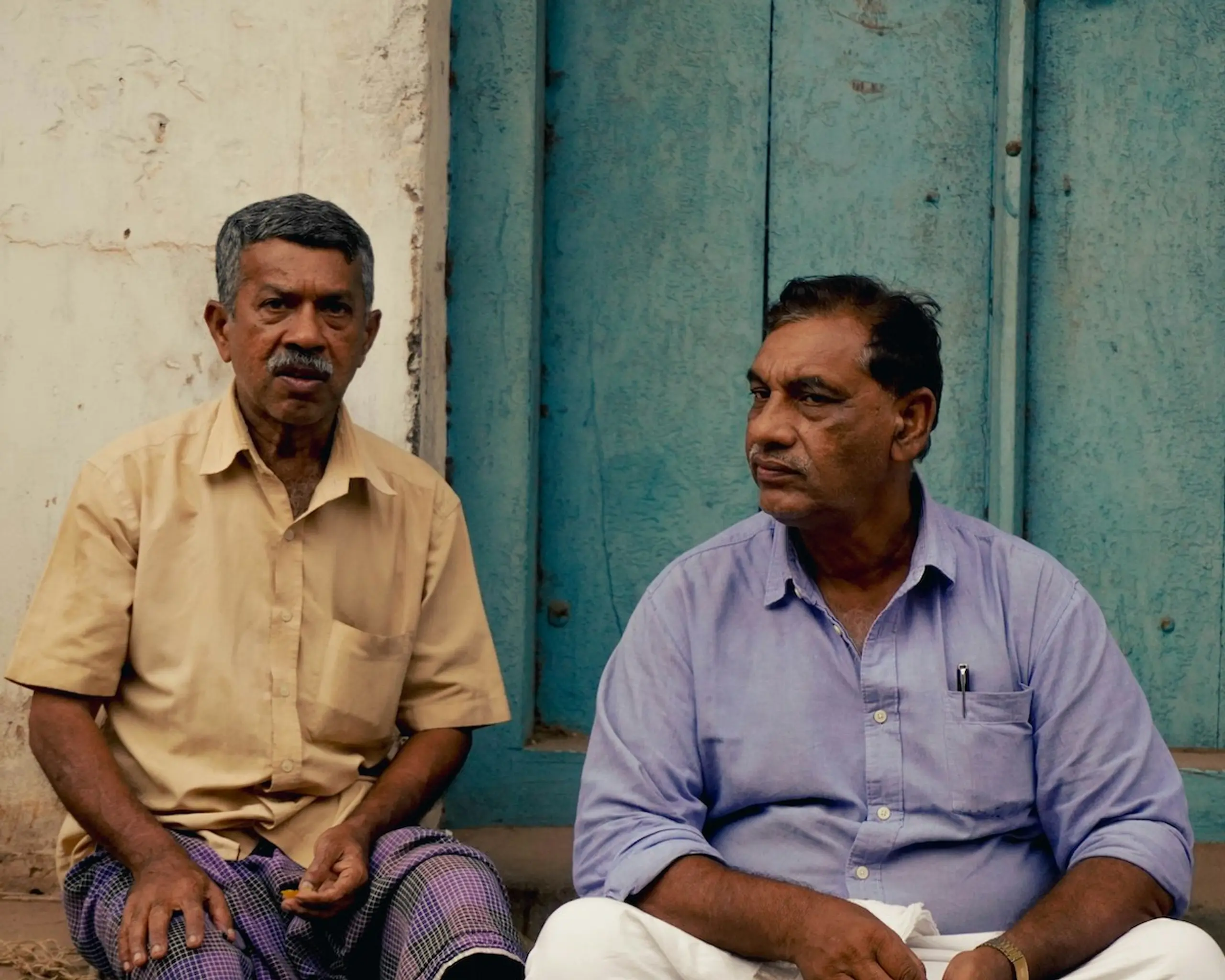 Two older men sitting together on the steps outside