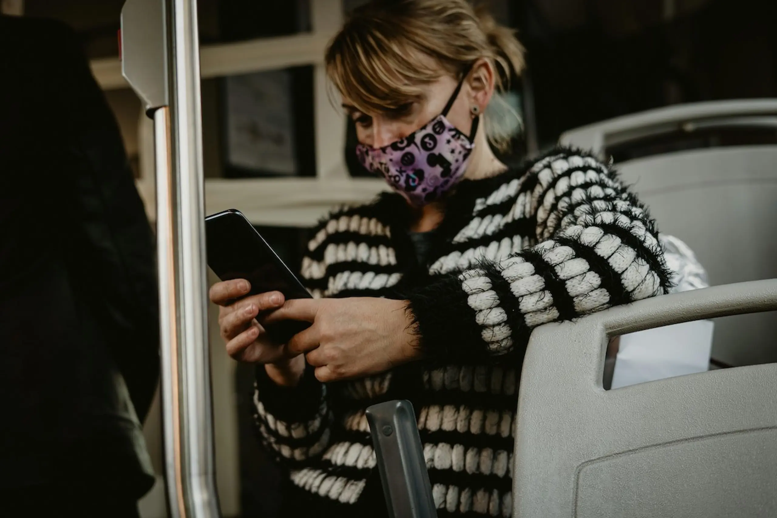 A woman wearing a mask while reading on the phone