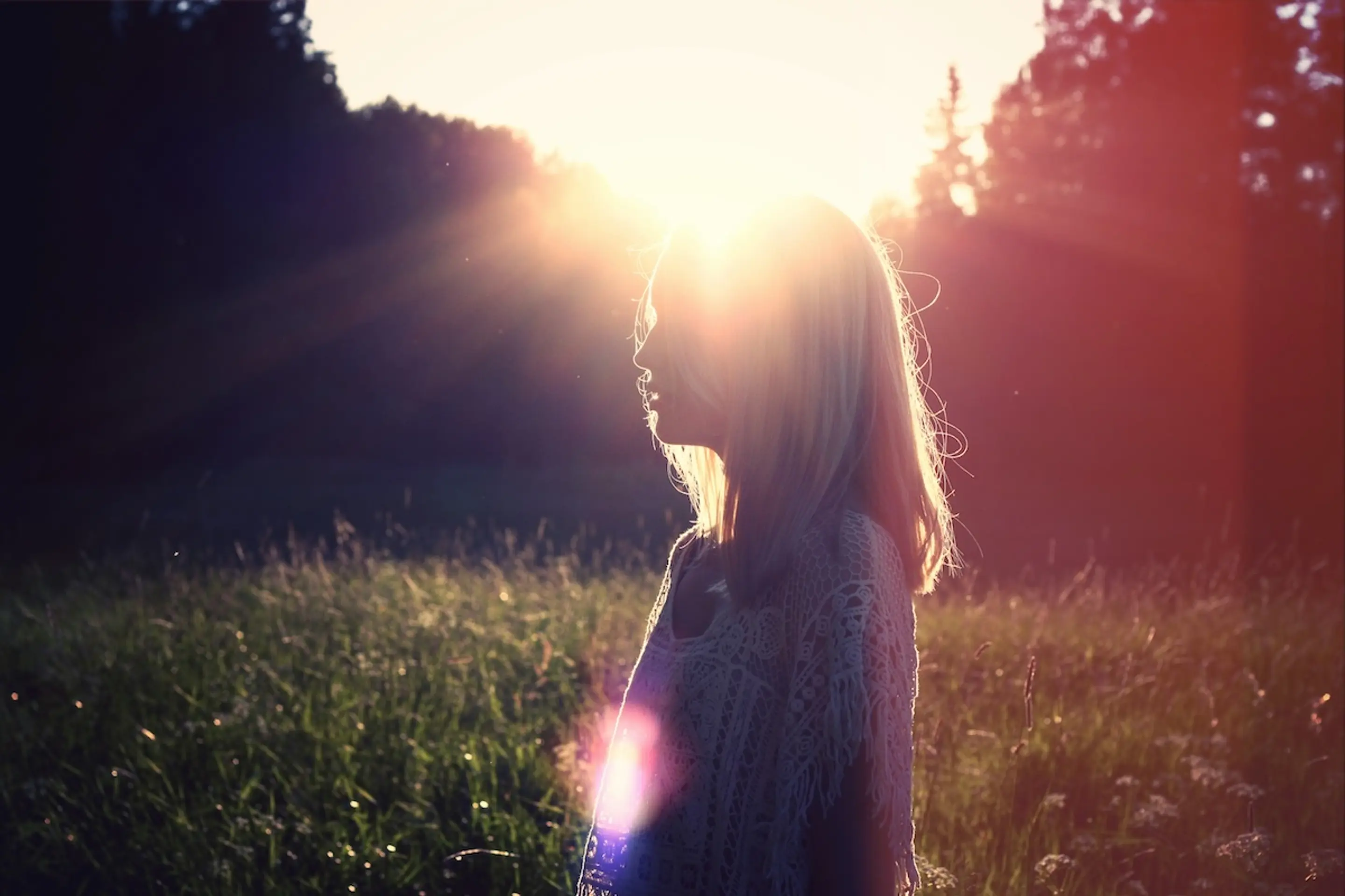 woman standing in grassy meadow with sunlight