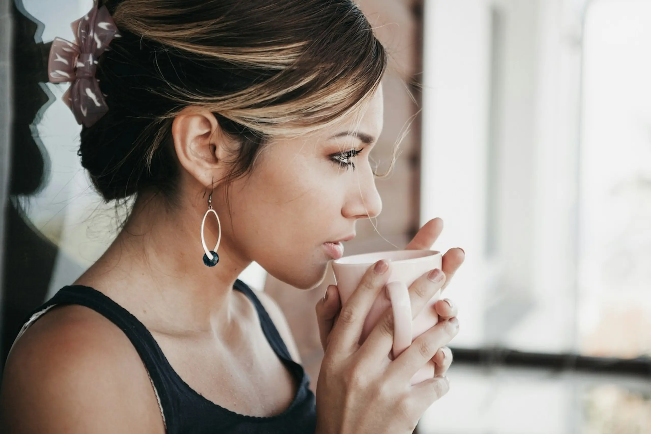 A concerned woman drinking tea while staring out the window