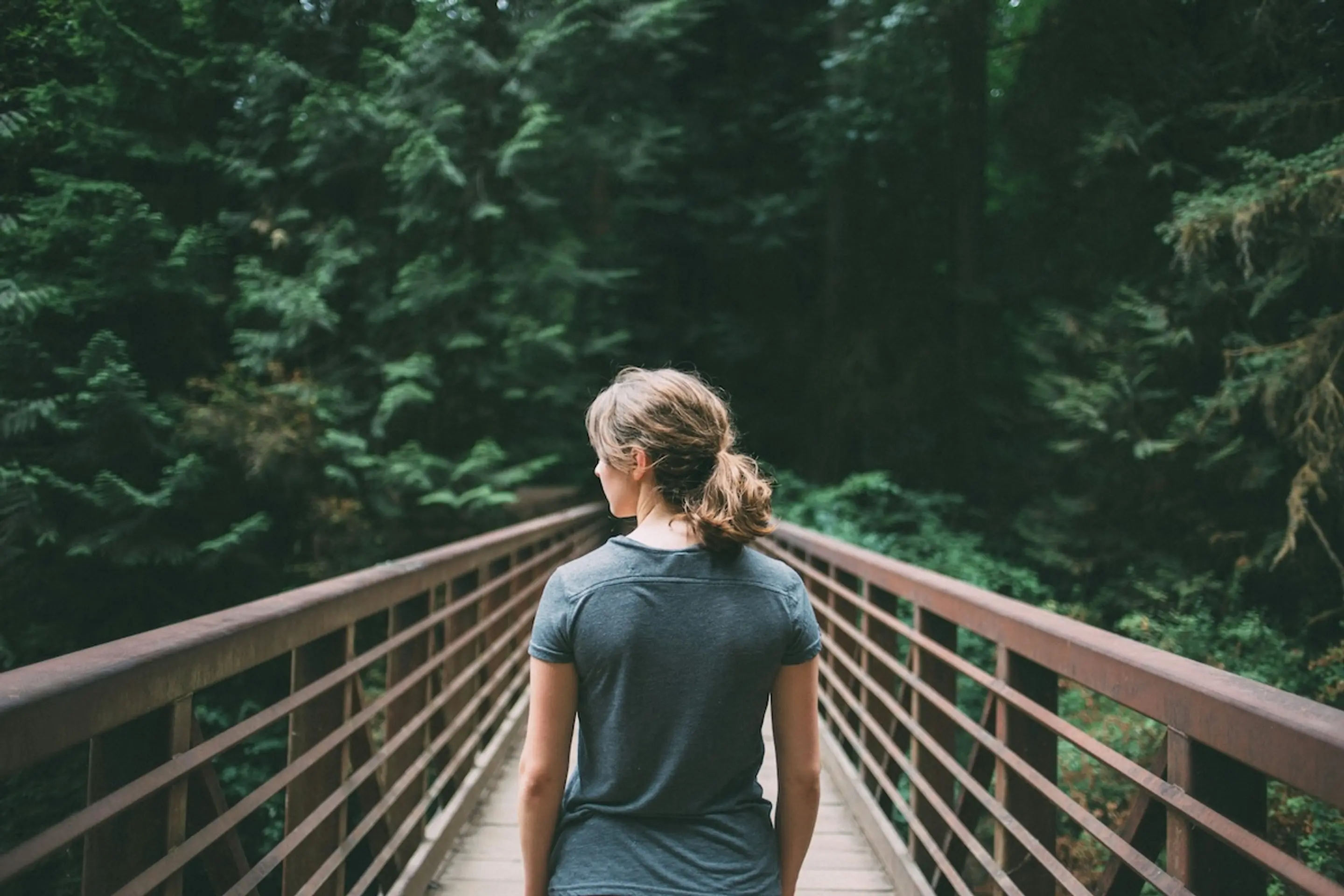 woman standing on bridge in the forest looking to her left