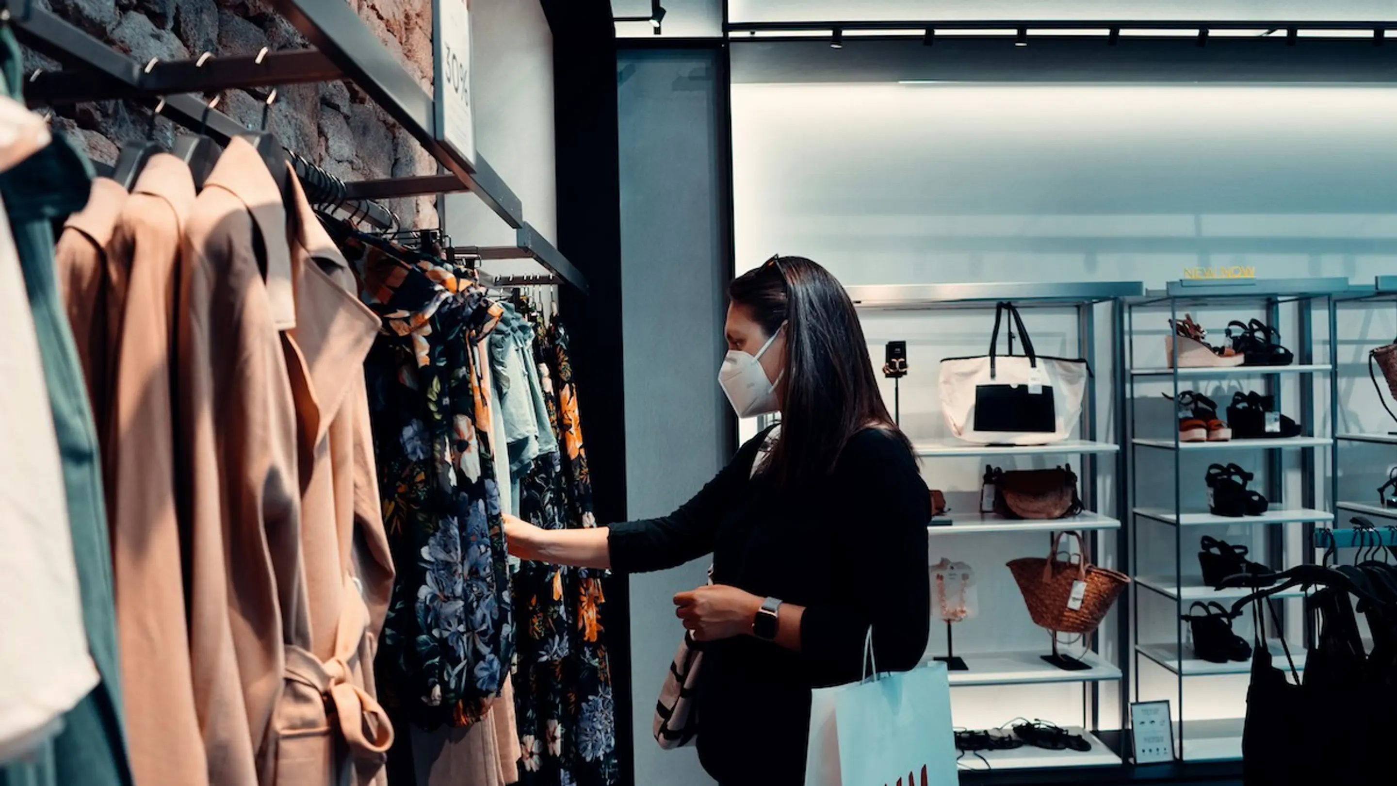 A masked woman looking at clothes at the store