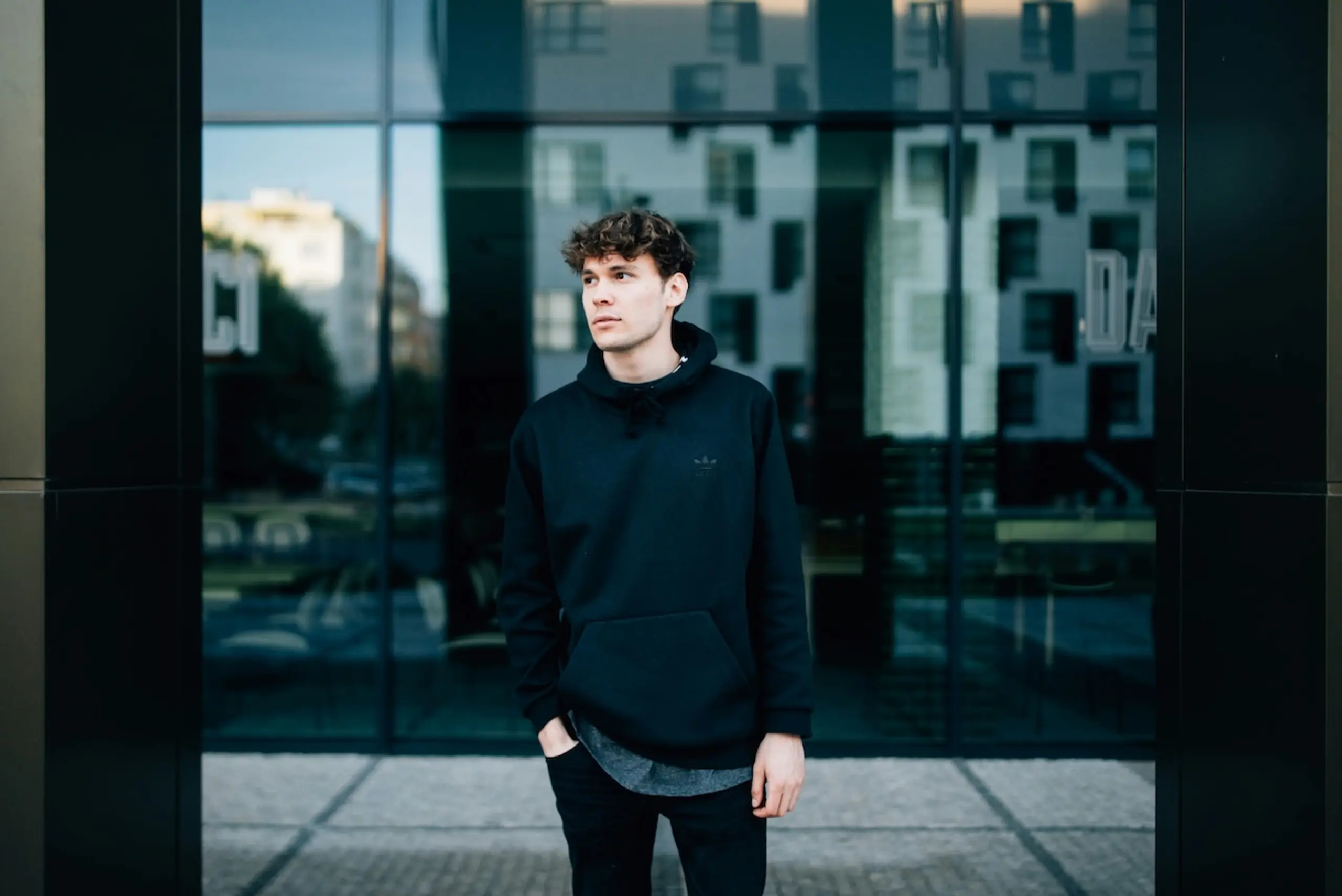 man standing in front of glass building in black sweatshirt