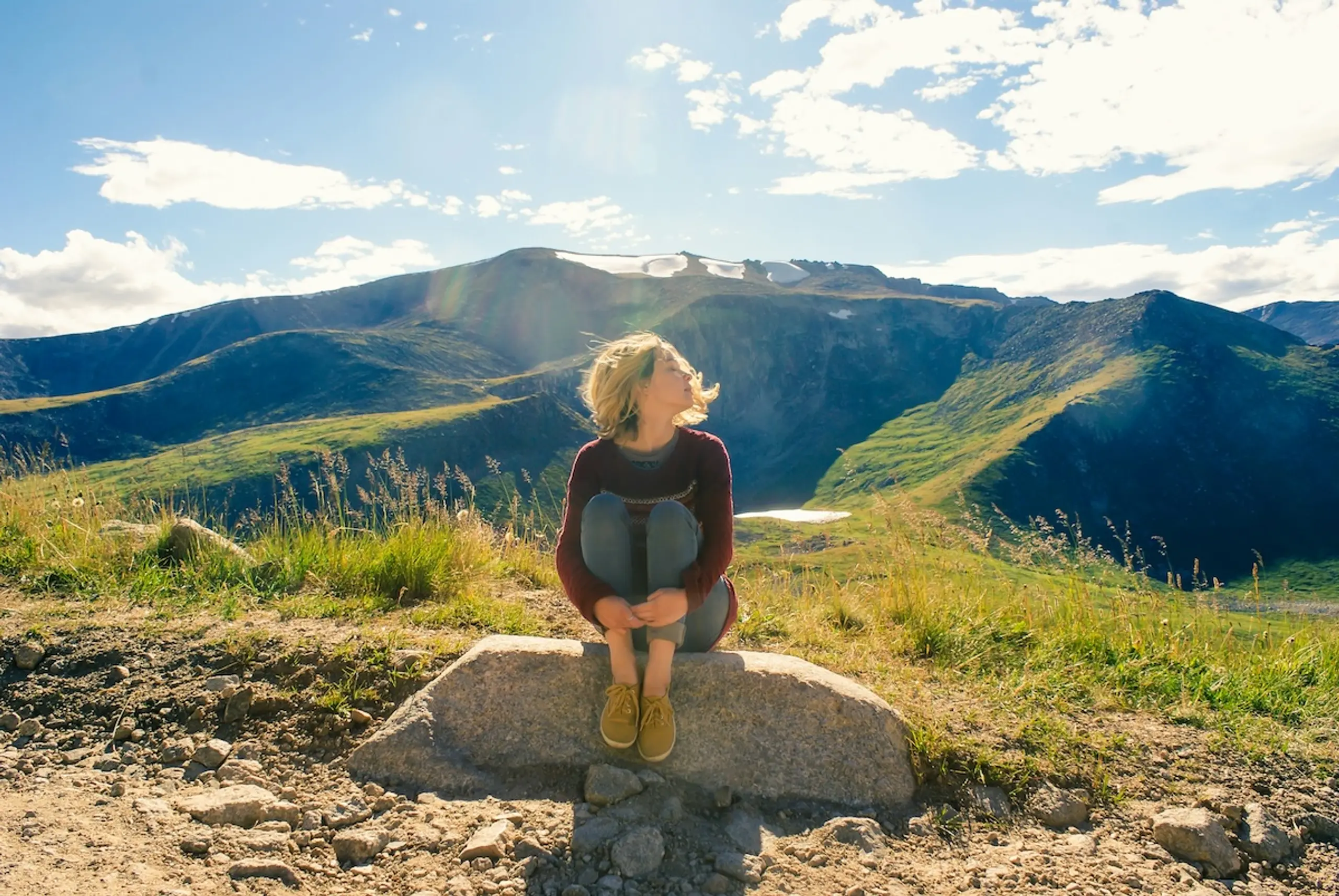 A woman sitting on rock next to mountain