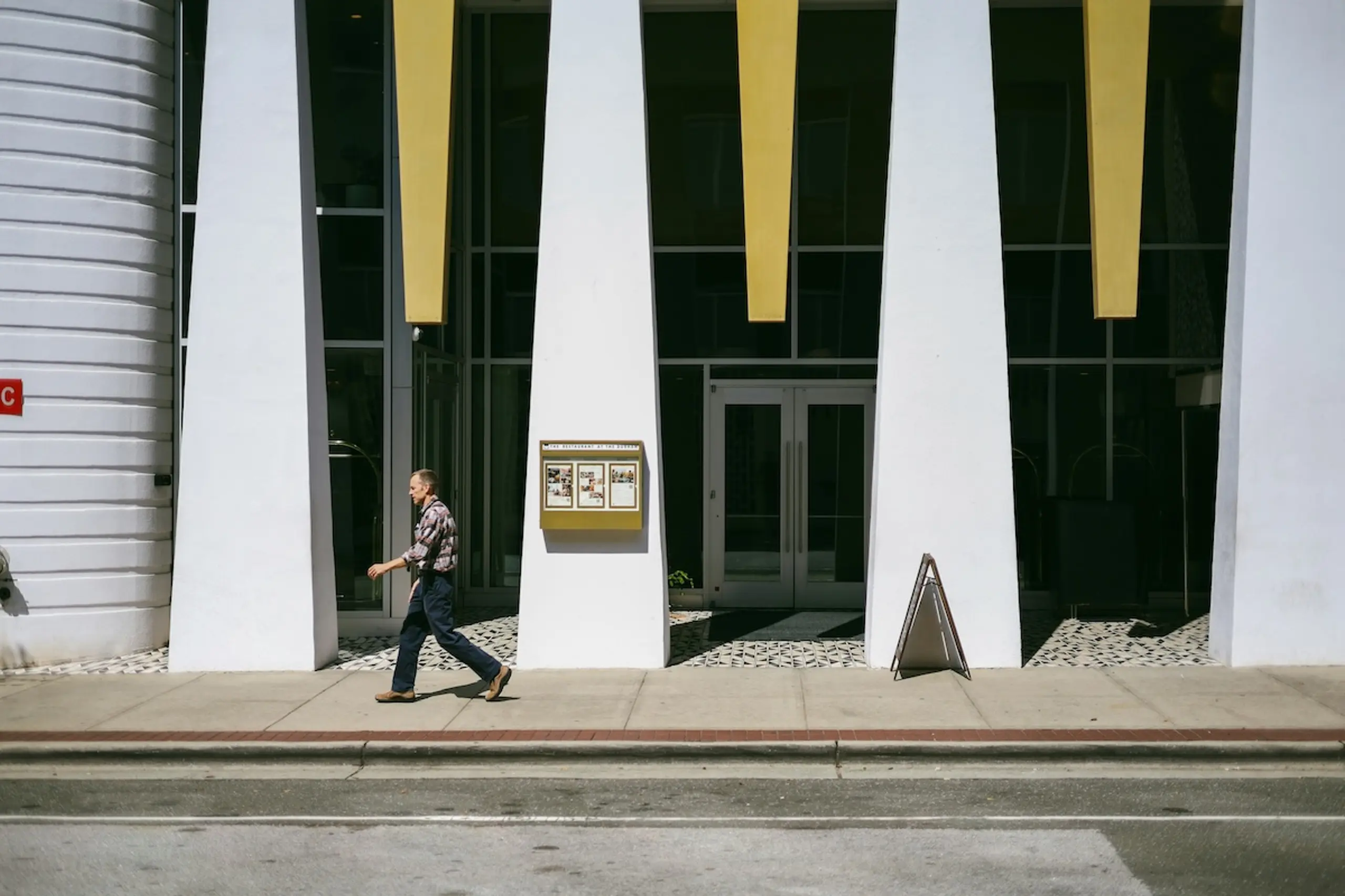 person walking on sidewalk in front of building entrance
