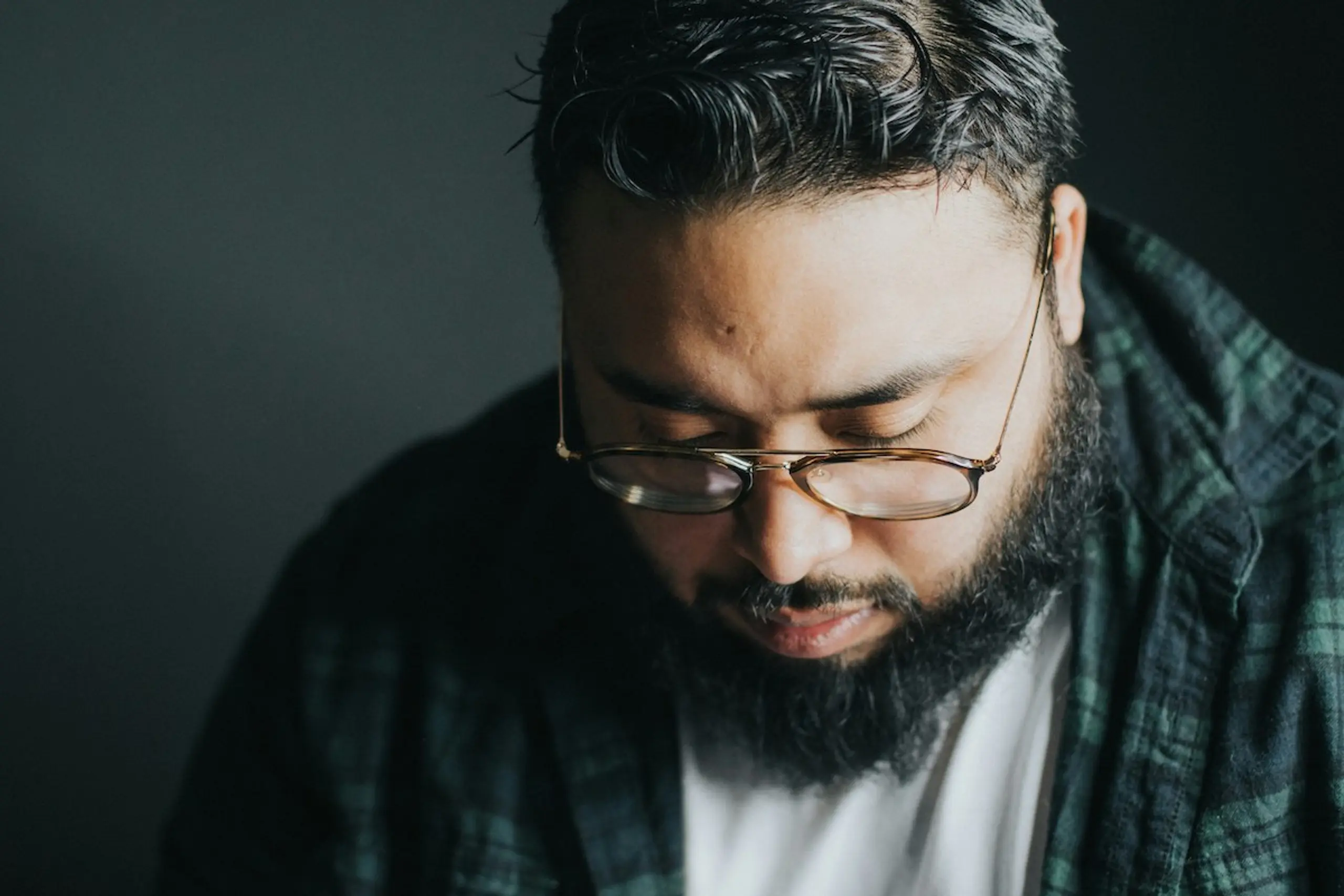 A man wearing glasses and looking down