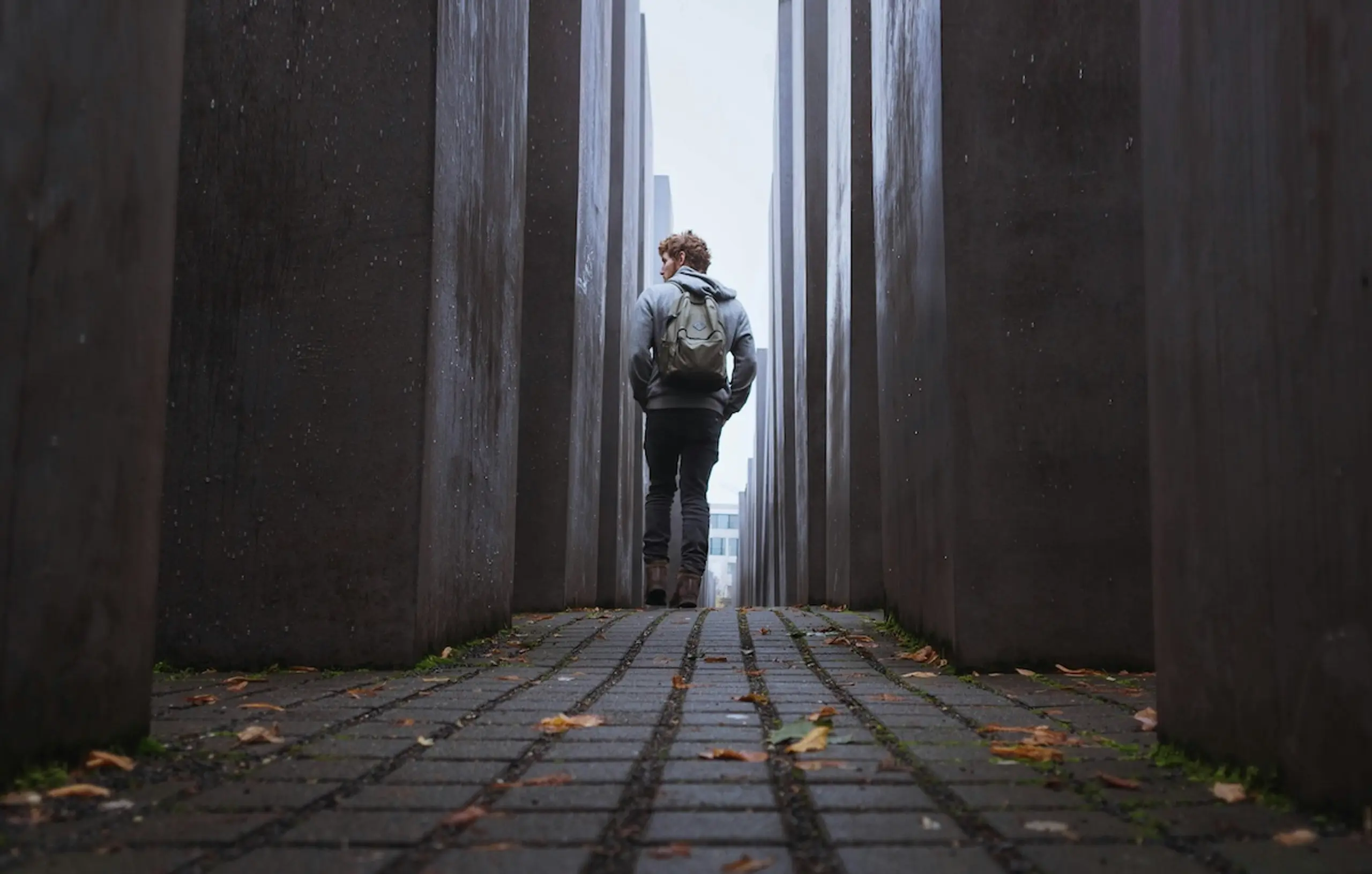 man walking down alley carrying backpack