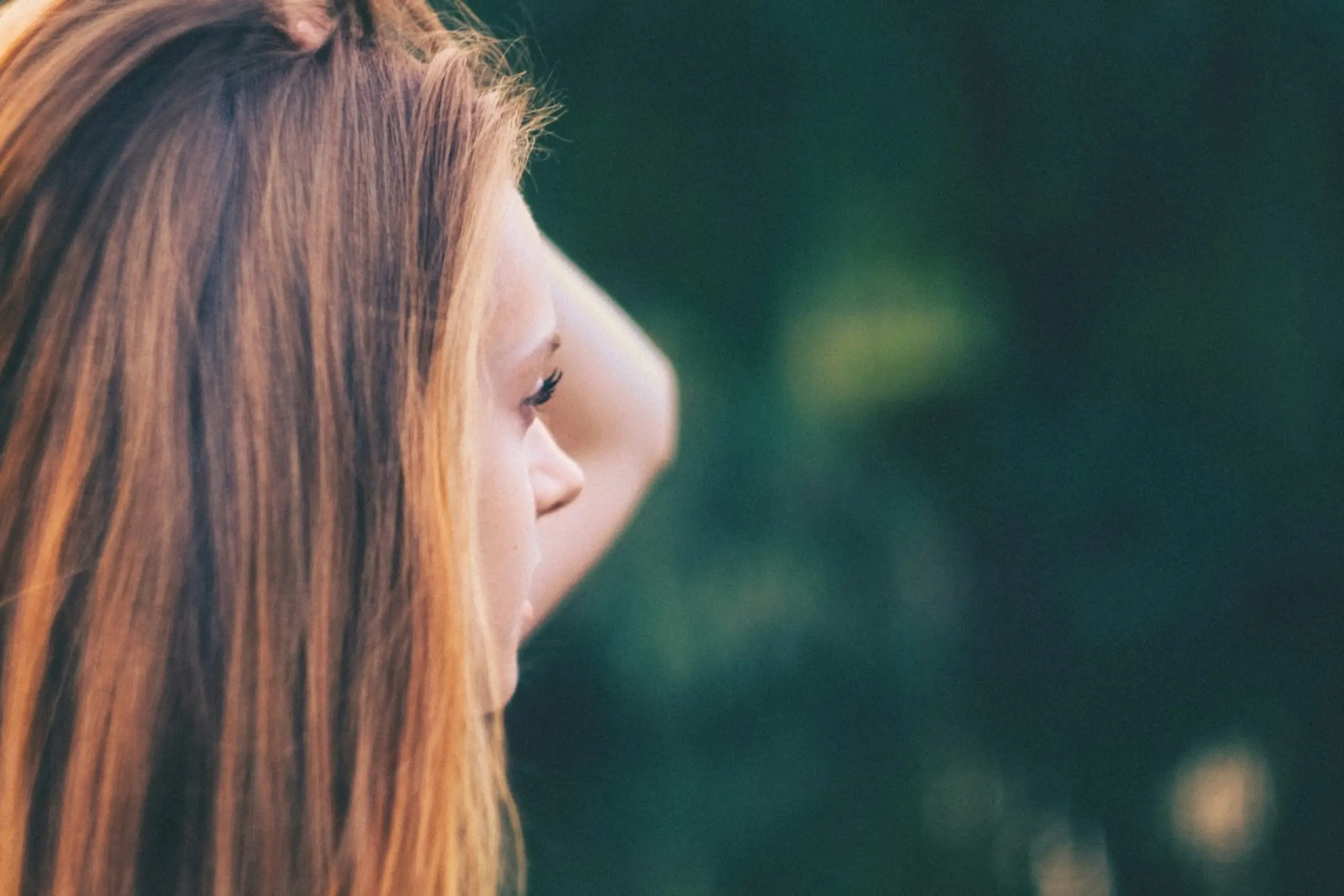 A woman staring off into the distance with her hand on her head