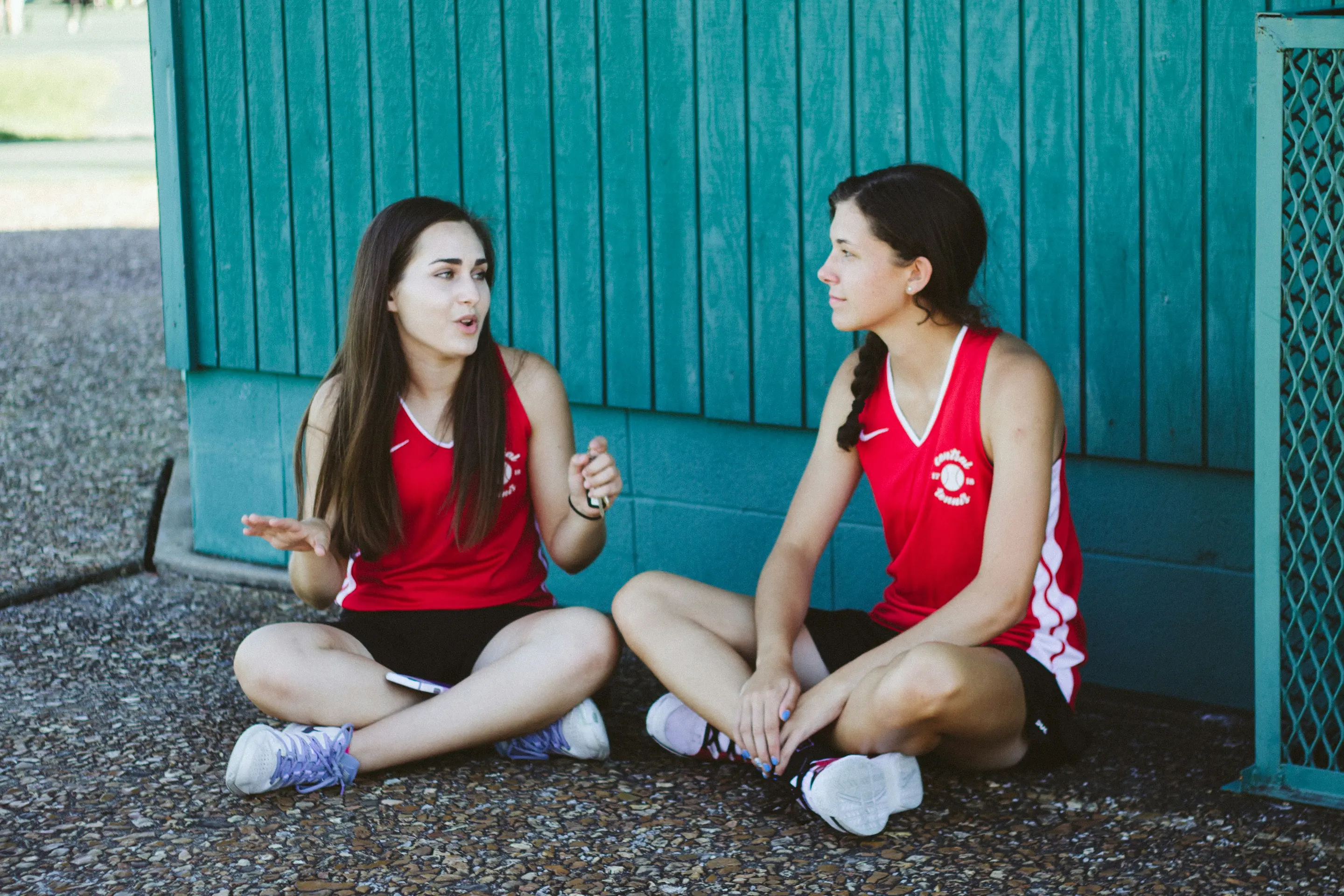 Two women talking while sitting on the ground outside