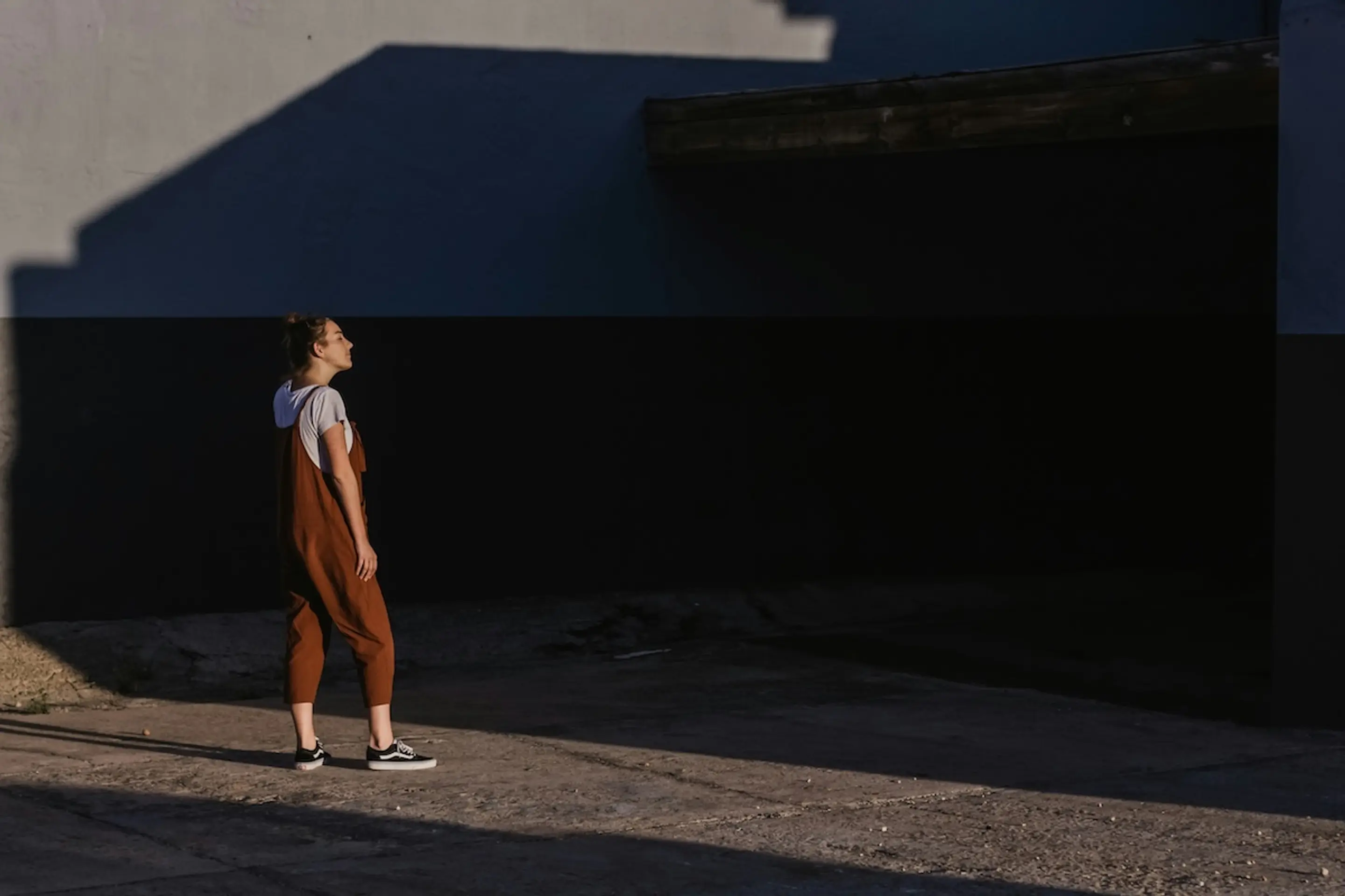 woman looking at shadows next to building