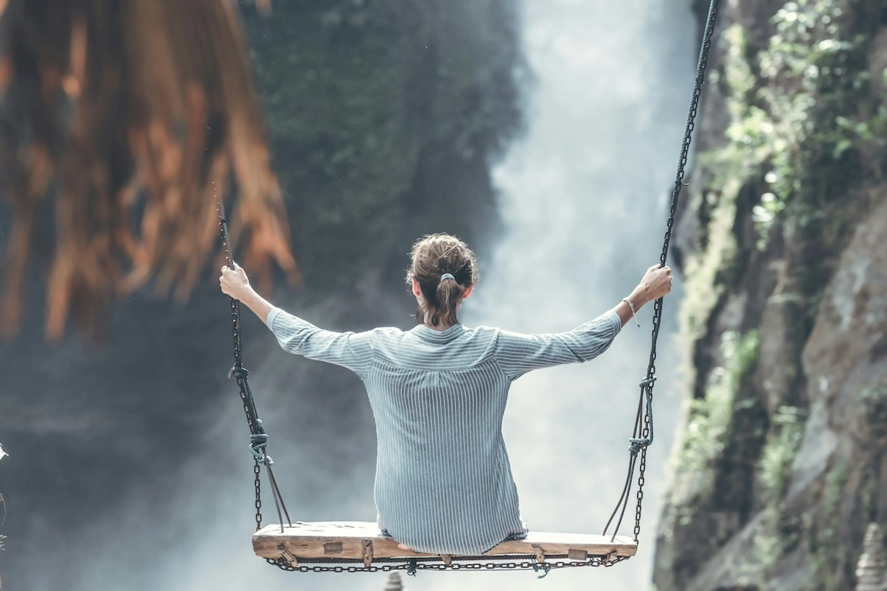 woman on swing looking at waterfall