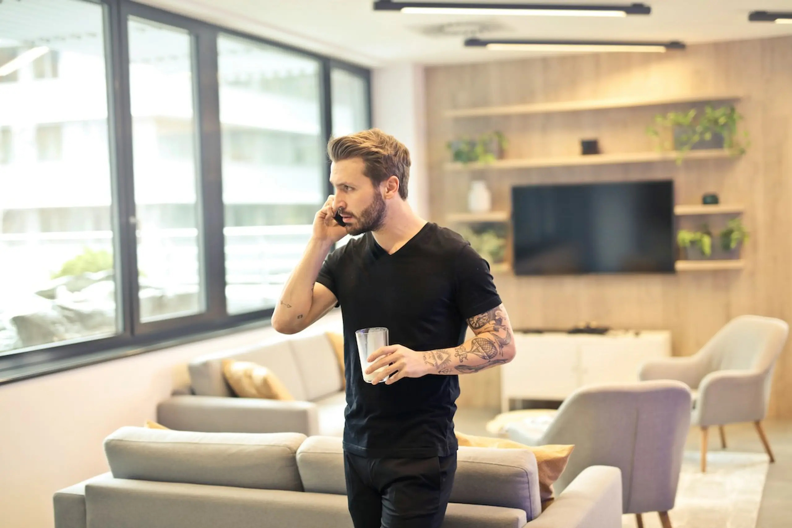 A man on the phone with a glass of water