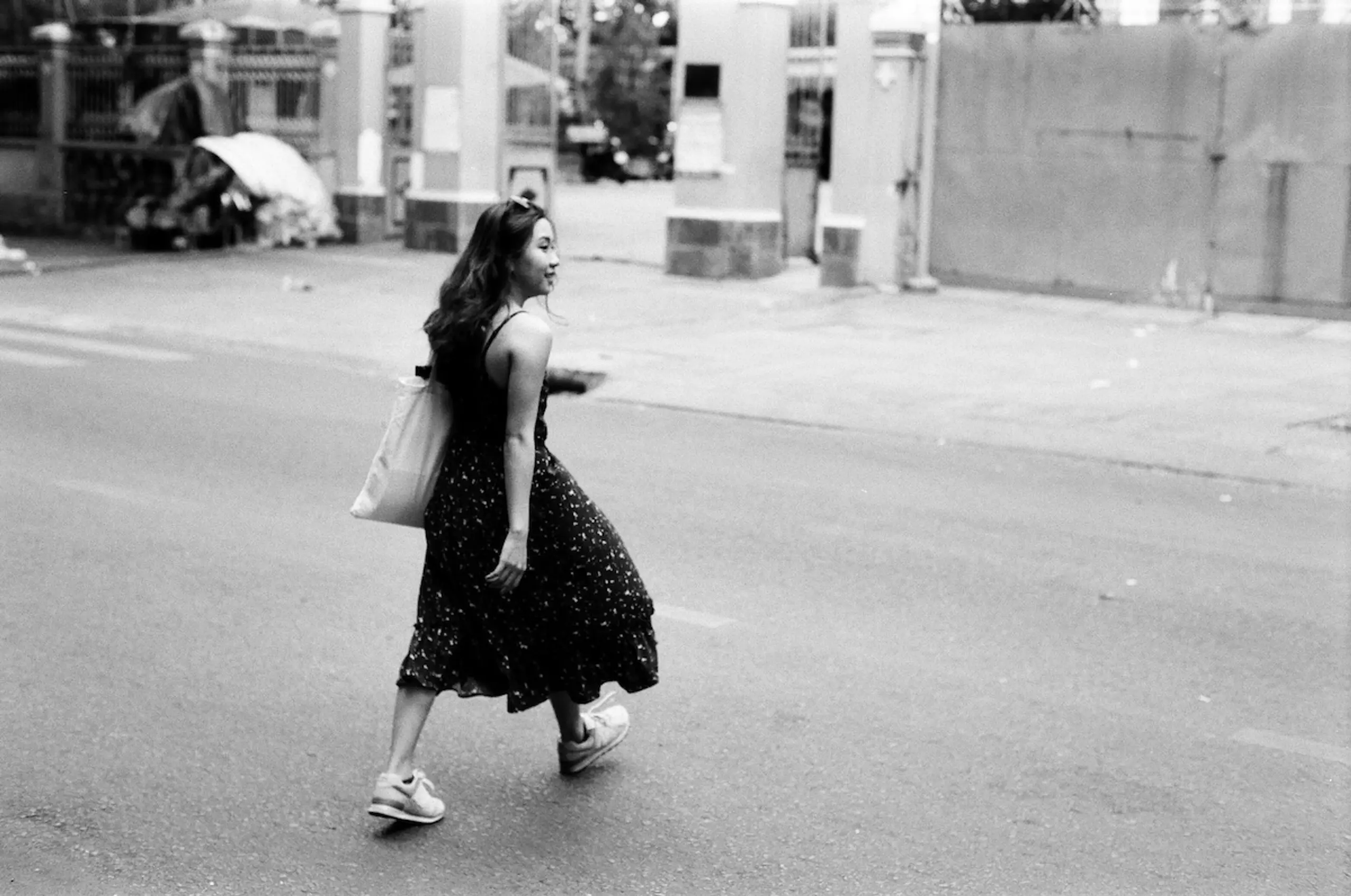 woman walking across street in dress and sandals with purse