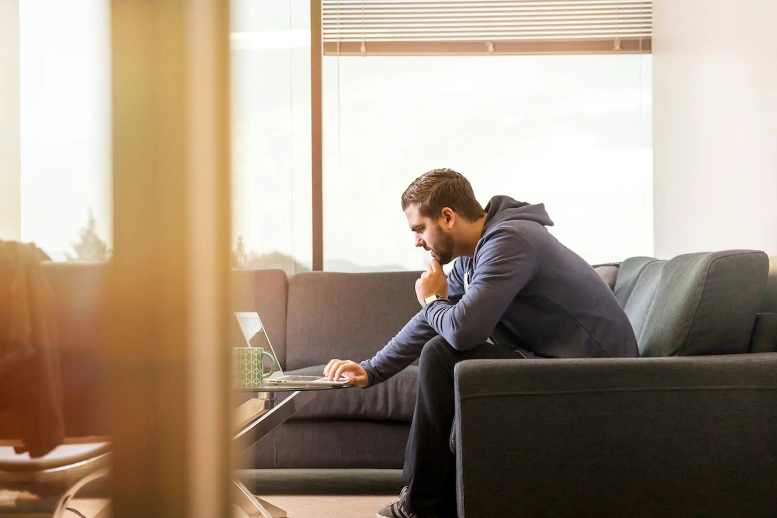 A man researching on the computer while leaning forward on the couch