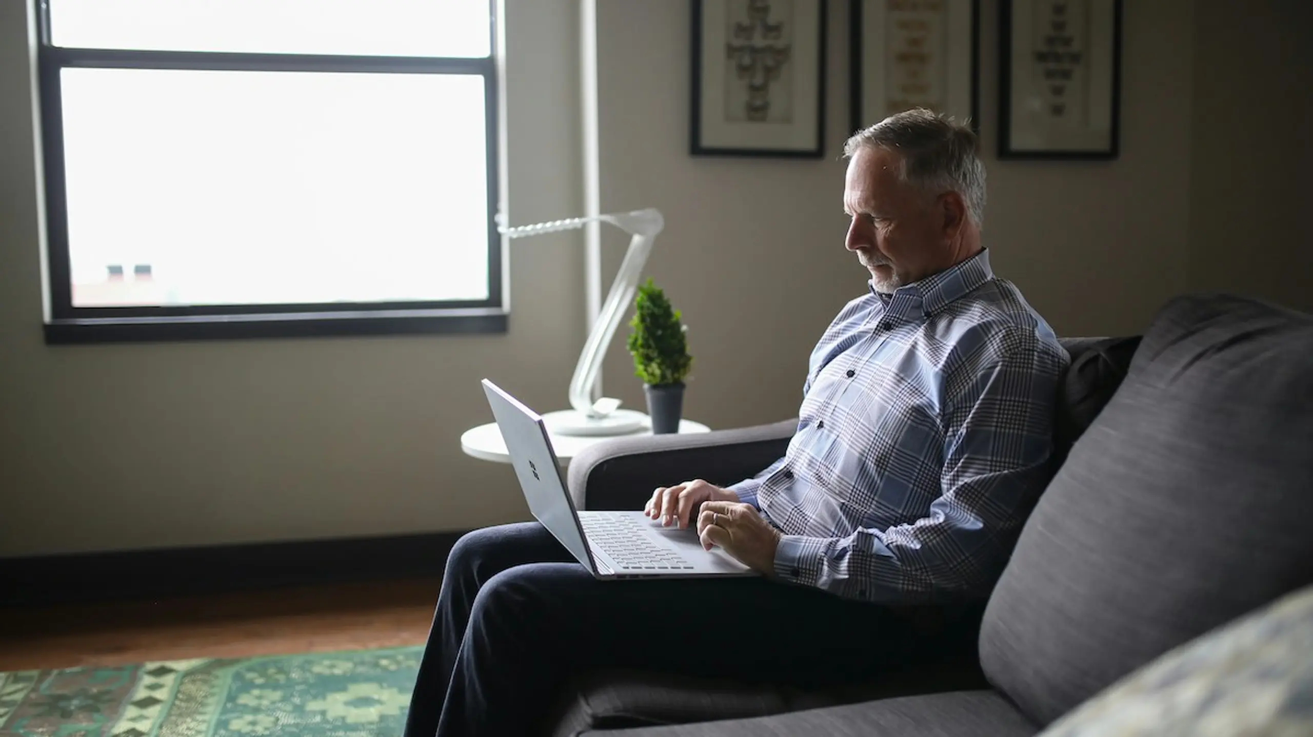 An older man on the couch using the computer