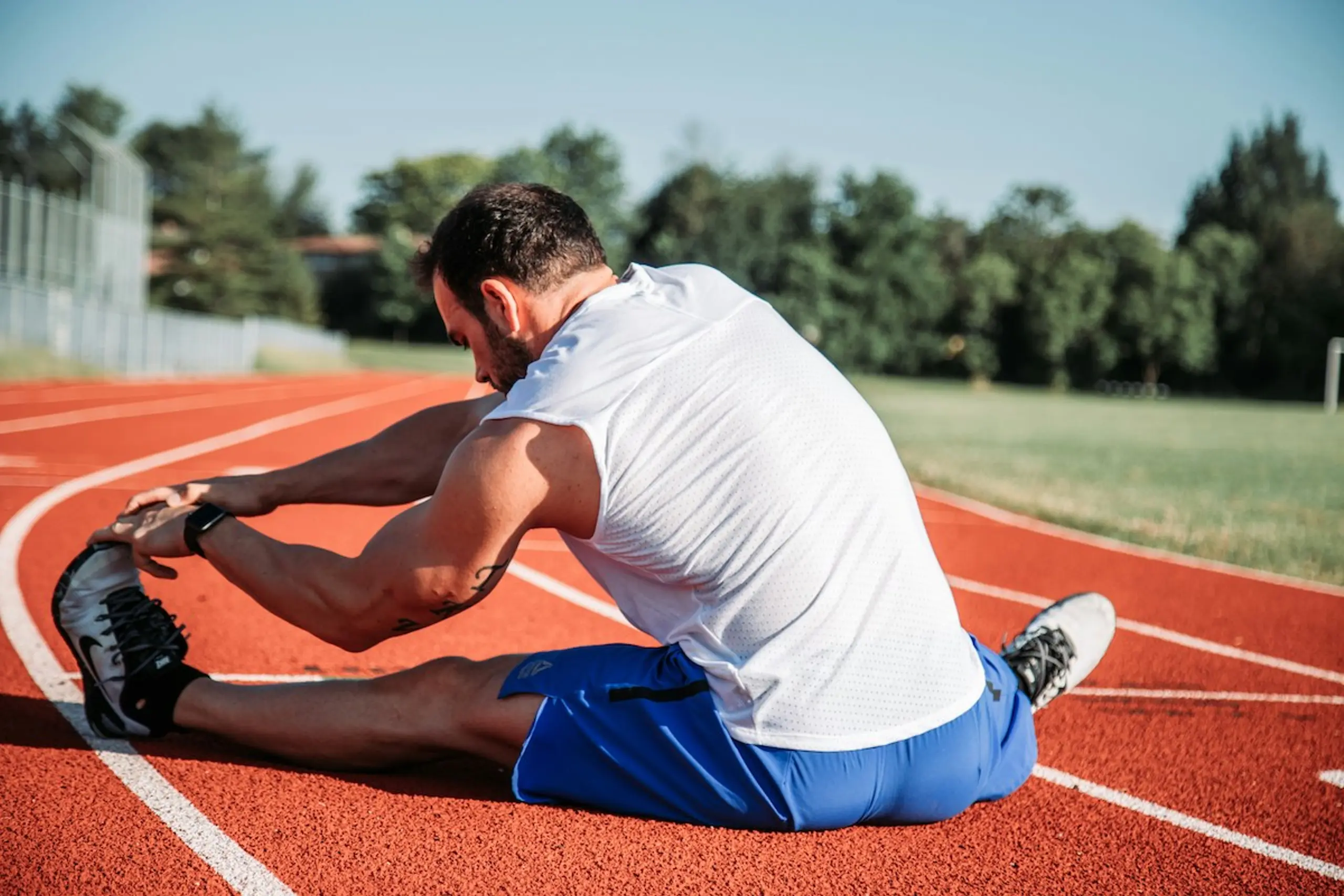 A man stretching his legs on a track