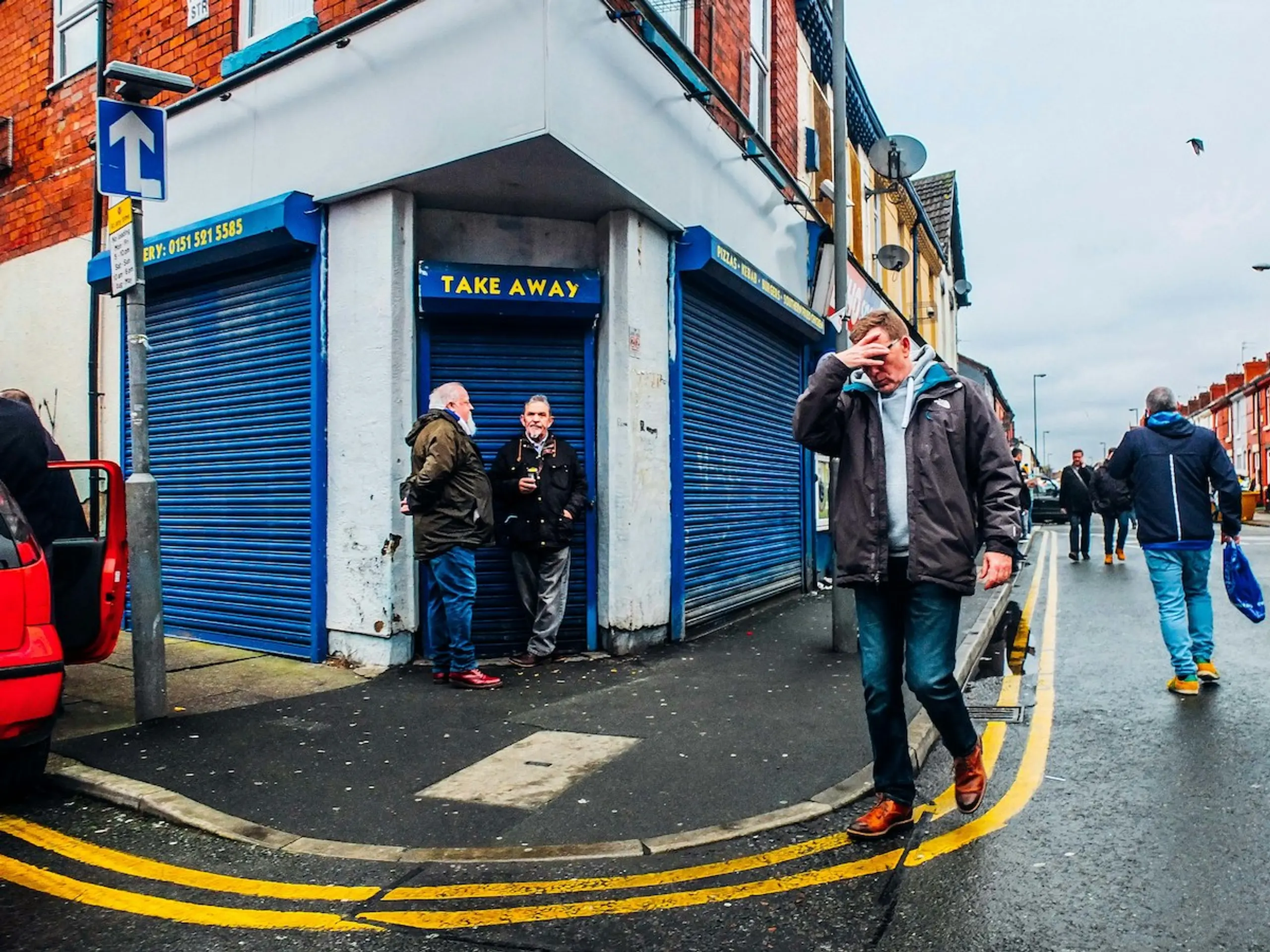 A man with his hand on his head walking on the street outside