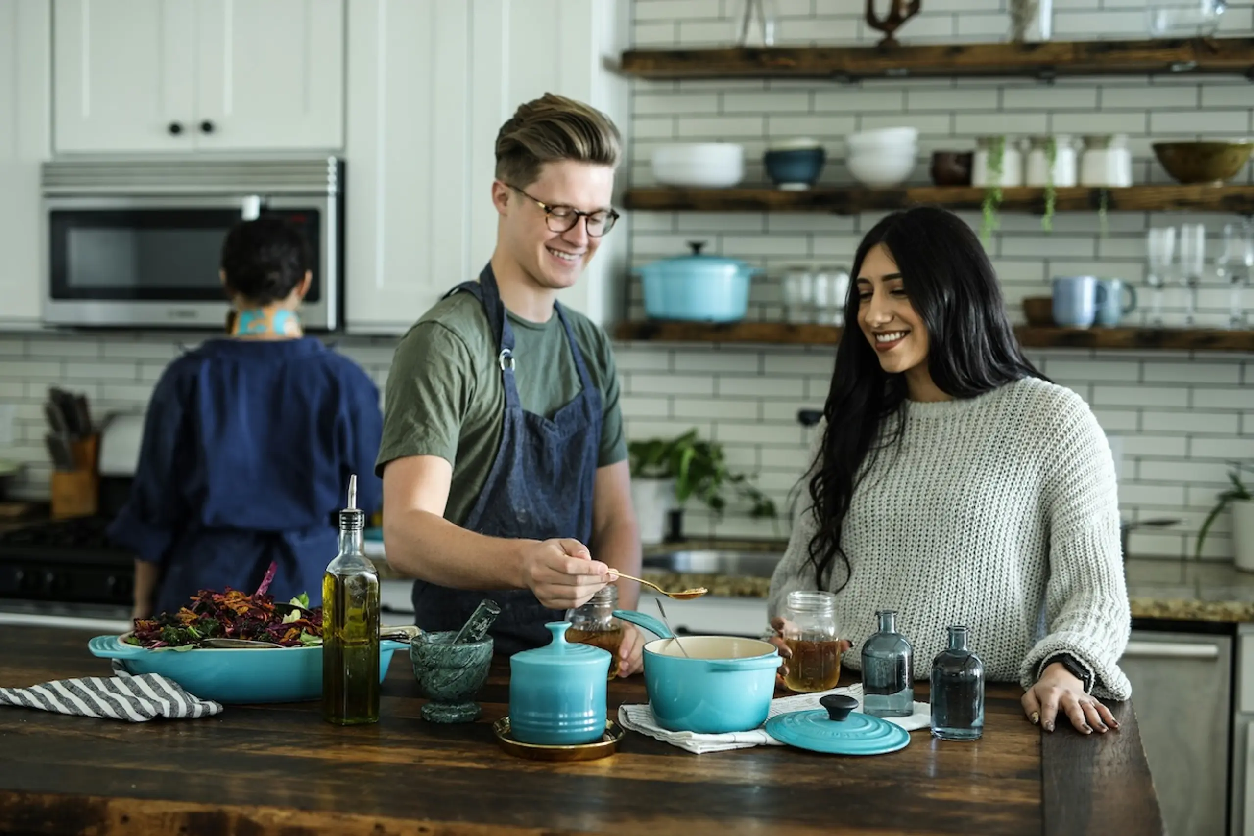 man and woman cooking together in a shared kitchen with blue pans