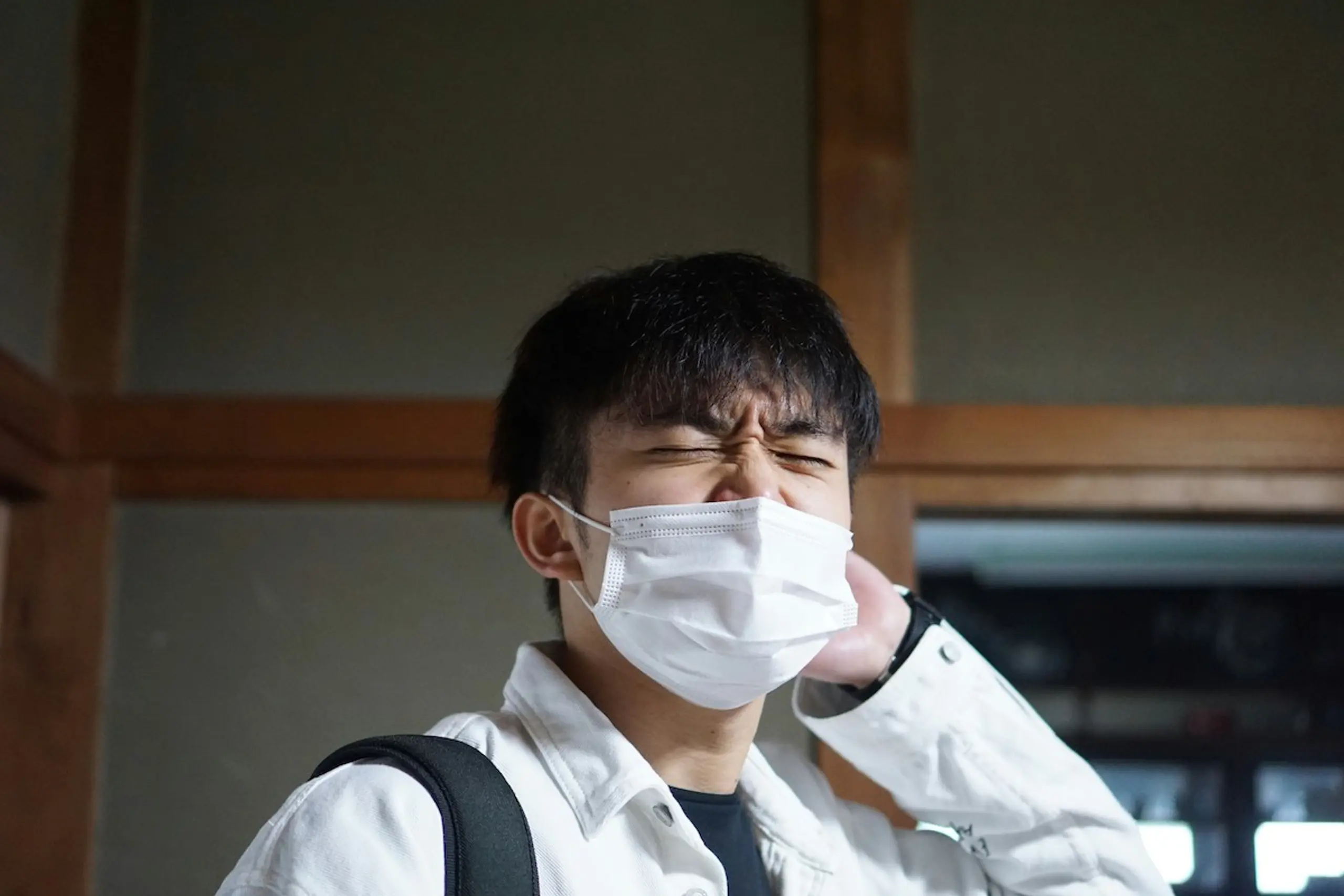 A man wearing a mask and is about to sneeze