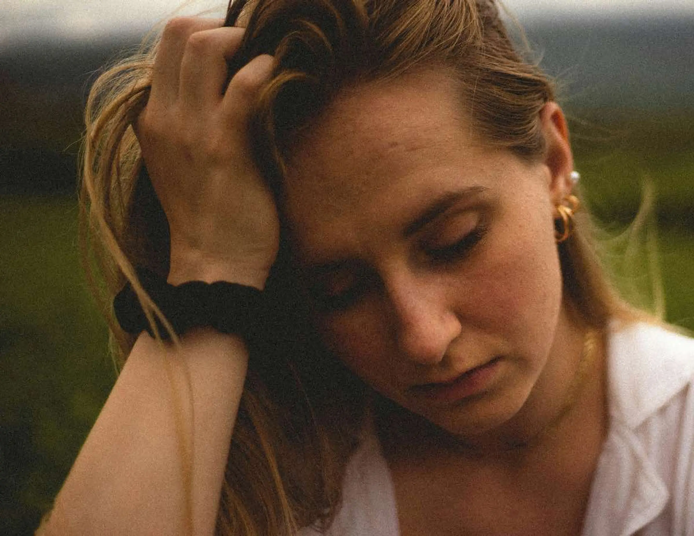 A woman with her hand on her head looking down