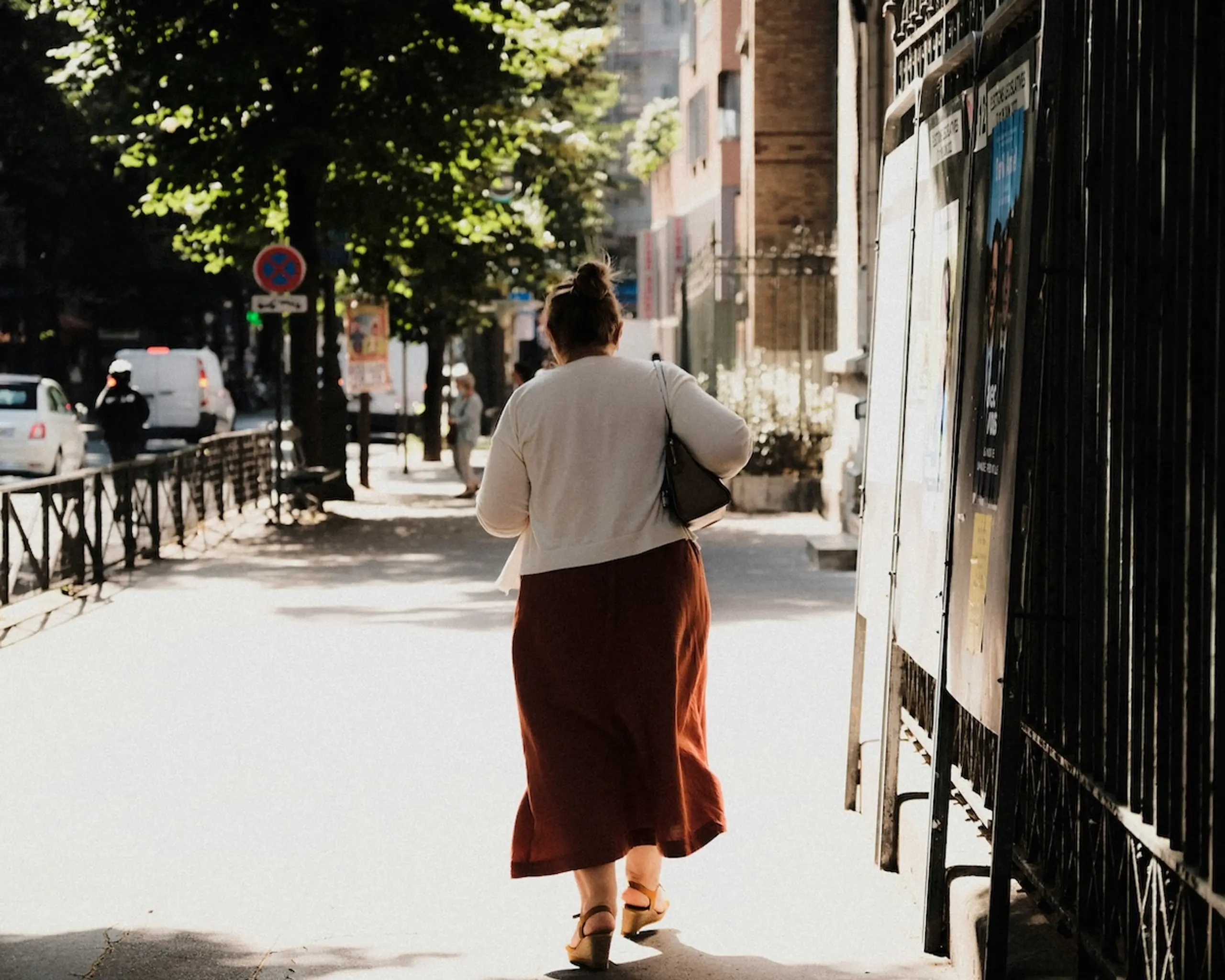 woman walking down city sidewalk during the day